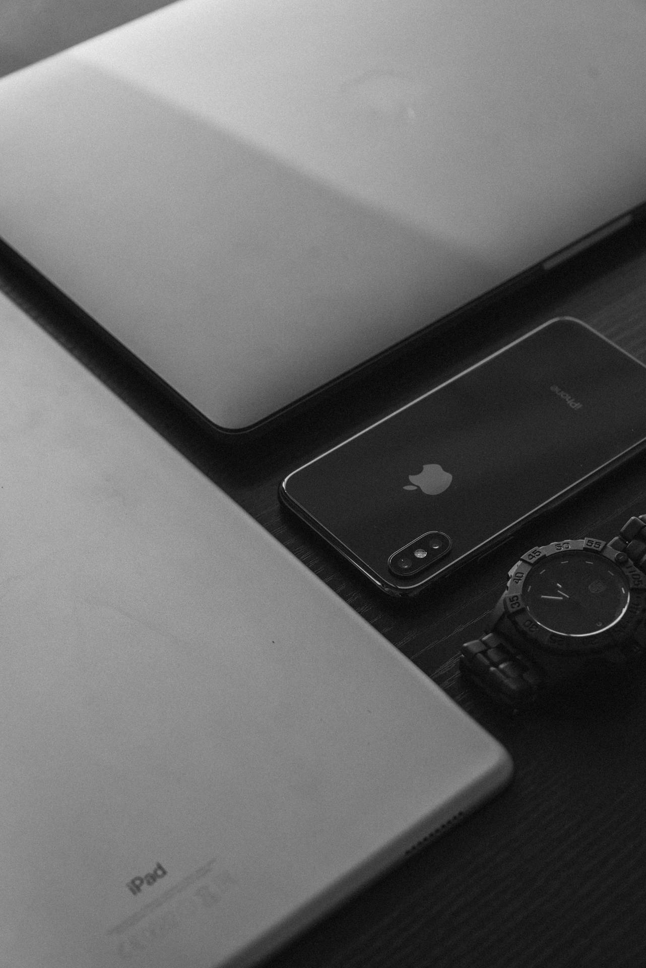 Apple 裝置和手錶在木桌上的黑白照片。