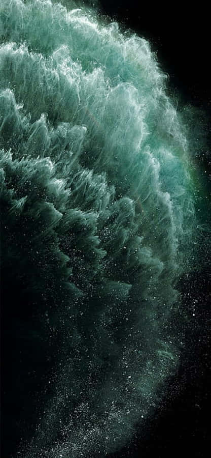 Apple iPhone X AMOLED 藍色星雲 壁紙 — 一道高聳的藍綠色波浪撞擊黑暗，激起泡沫般的白色飛沫和懸浮在運動中的閃爍水滴。