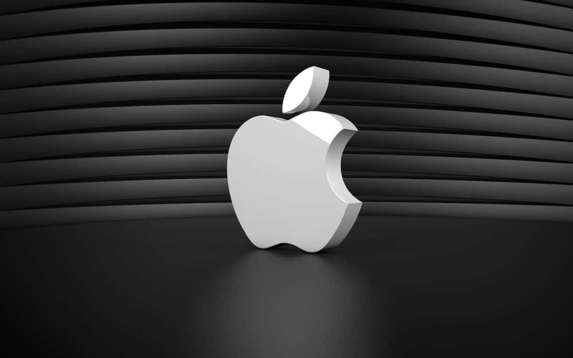 優雅 Apple 筆記型電腦擺放在極簡工作空間 壁紙 — 一個時尚的銀色Apple標誌置中在深色表面上，背景是彎曲的黑色條紋牆。