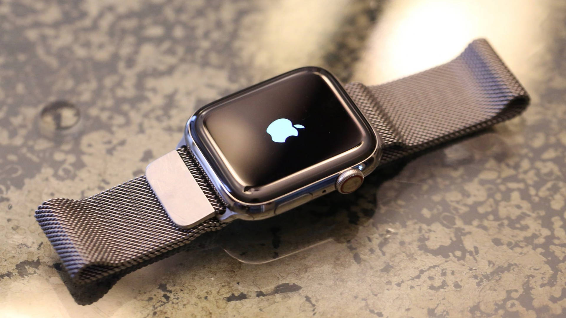一款現代的Apple Watch搭配網狀錶帶，放置在斑點檯面上。