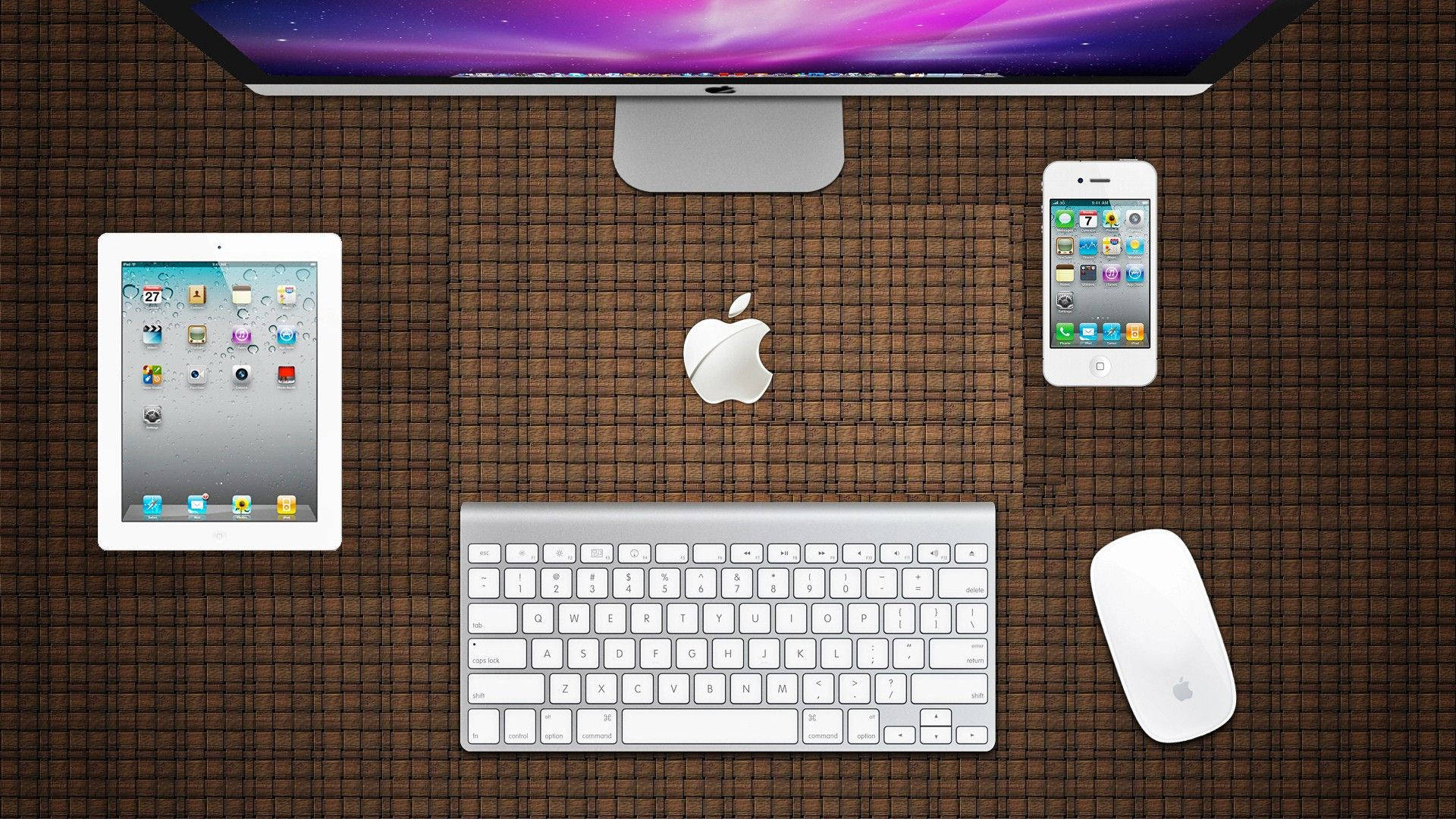 Apple產品辦公桌佈置 壁紙 — Apple 裝置（包括顯示器、平板電腦、電話、鍵盤和滑鼠）在棕色編織滑鼠墊上的俯視圖。