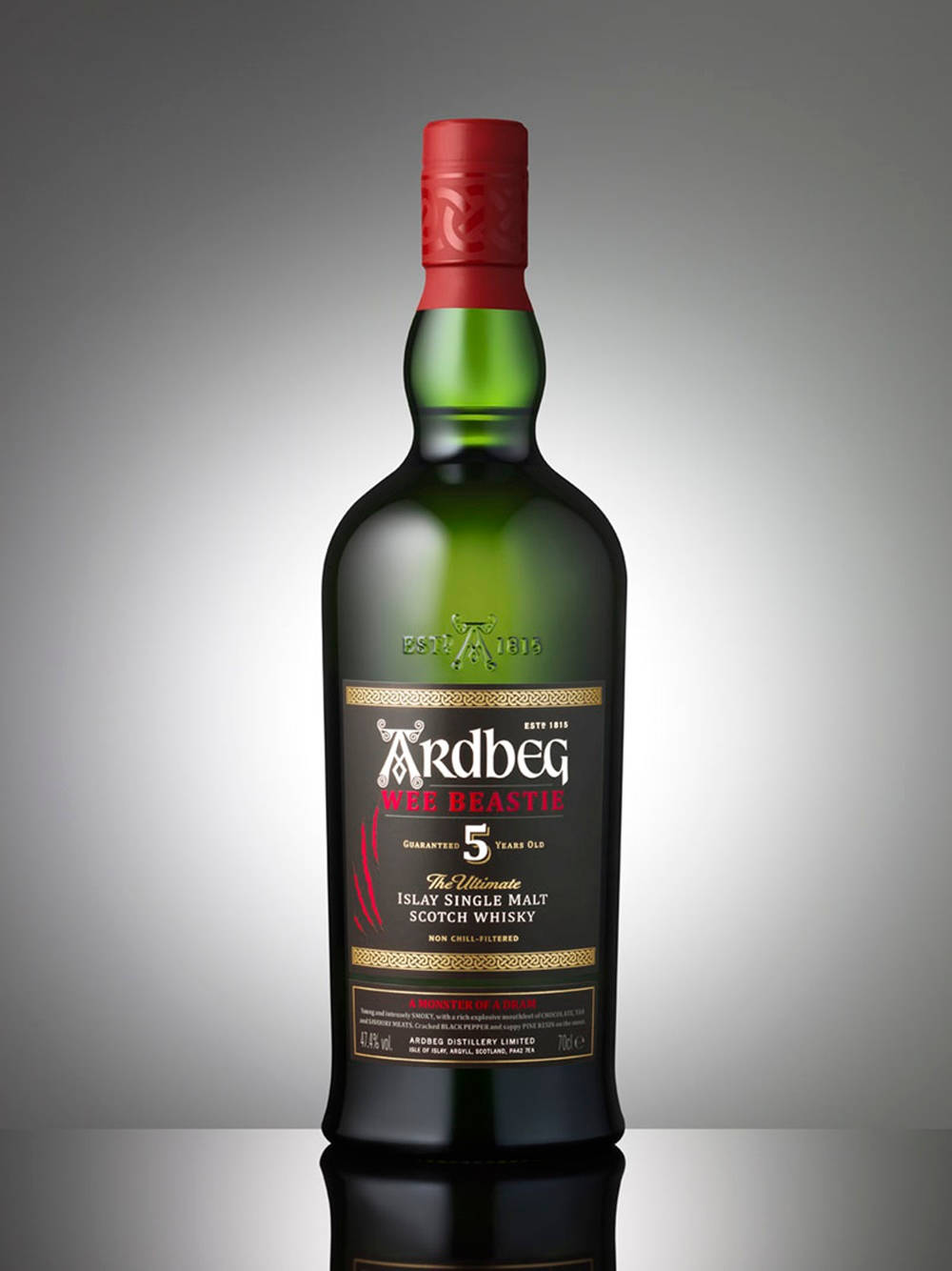 Ardberg Wee Beastie威士忌酒瓶，紅色瓶蓋，置於反射表面，灰色漸變背景。