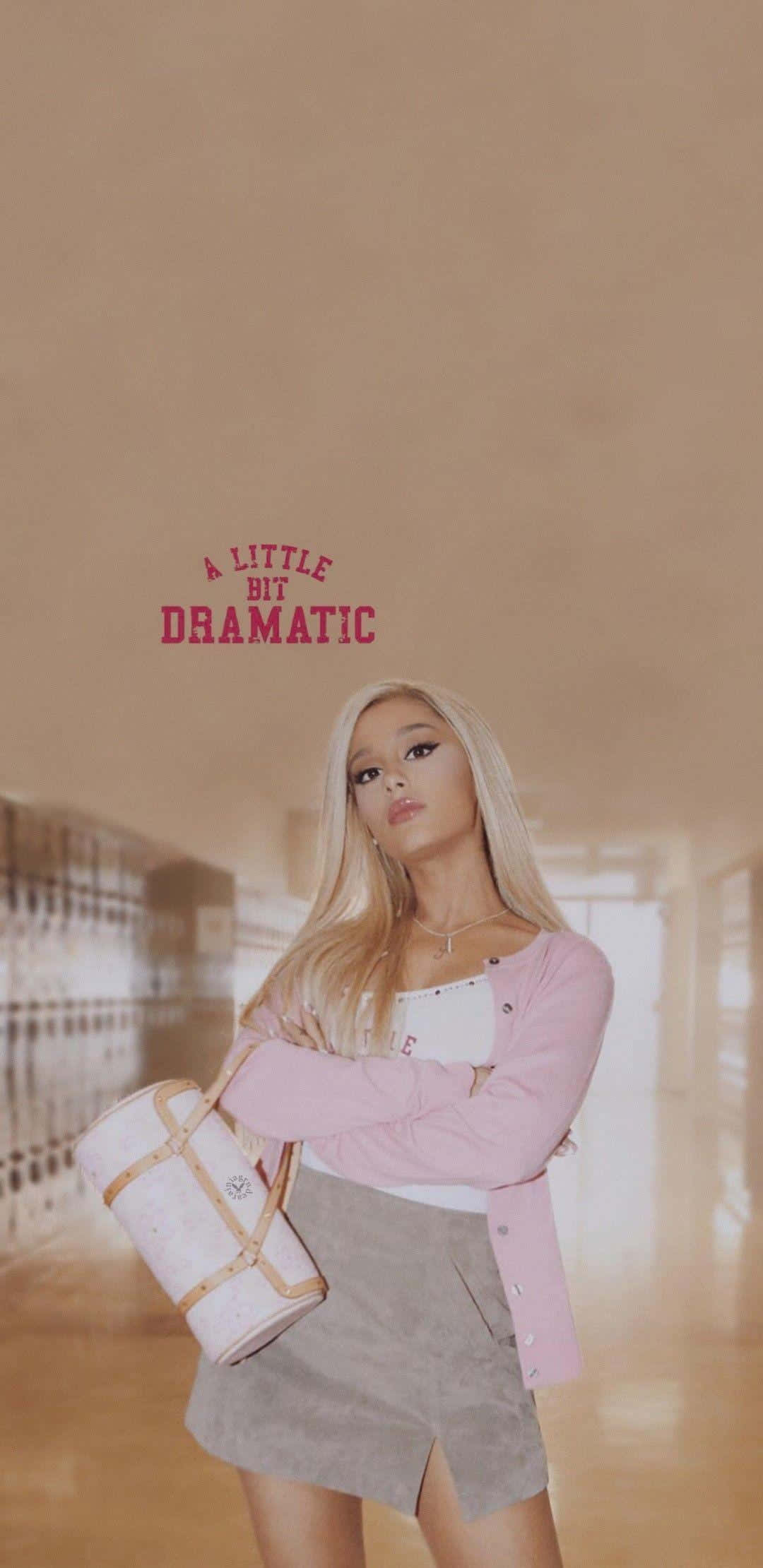 Aesthetic Ariana Grande 桌布 壁紙 — Ariana Grande 自信地站在學校走廊，身穿粉紅色和米色服裝，手持一個白色手袋，上方有文字。