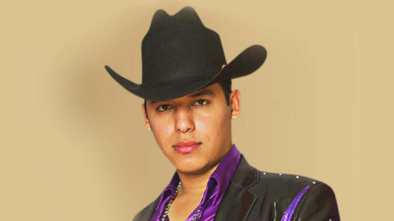 Ariel Camacho 黑白肖像照 壁紙 — 一位戴黑色牛仔帽、穿紫色襯衫的年輕男子在米色攝影棚背景下自信地凝視。
