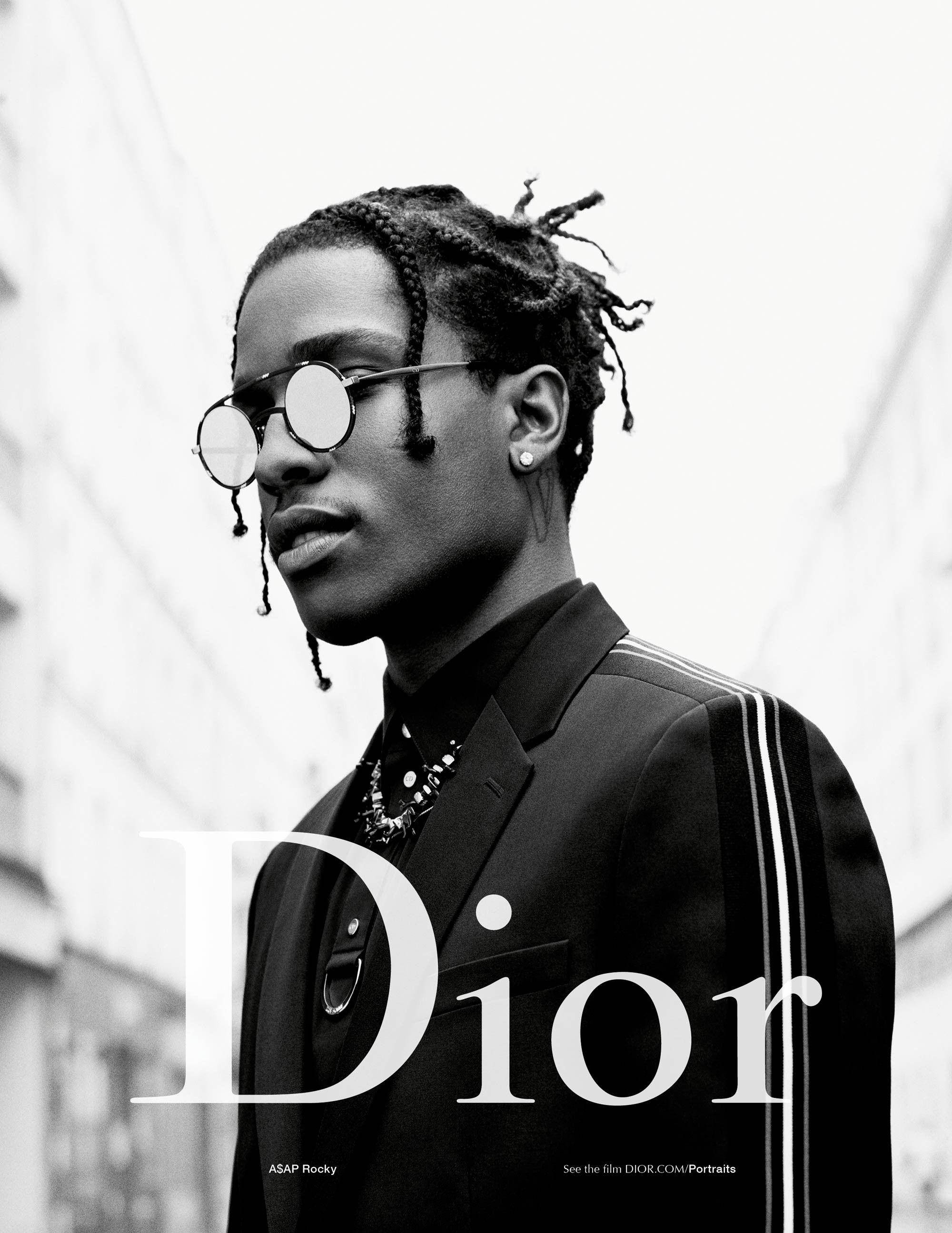 Dior Asap Rocky 壁紙 — ASAP Rocky 身穿訂製西裝和圓形太陽眼鏡的黑色和白色肖像，背景是模糊的城市景觀。
