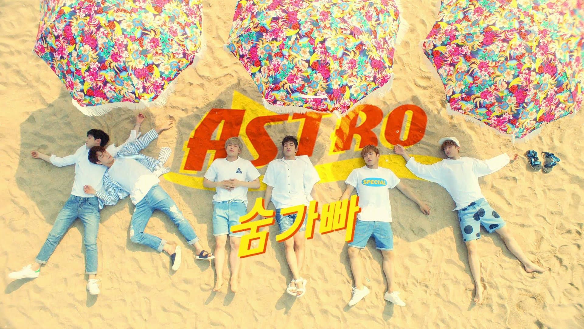 韓國男子團體Astro 壁紙 — 六個穿著白襯衫和藍色短褲的男人躺在沙灘上，在色彩繽紛的花卉傘下，傘上有粗體橙色文字。