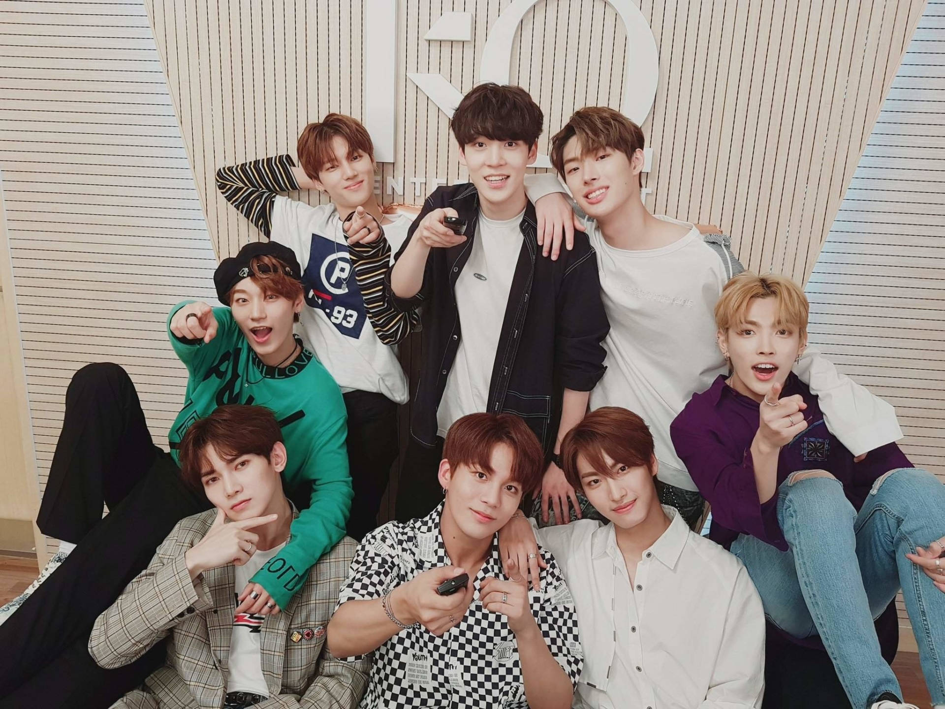 Ateez合照桌面 壁紙 — 七名身穿休閒服裝的年輕男子在條紋牆前愉快地合照，背景有一個大的白色數字「20」。