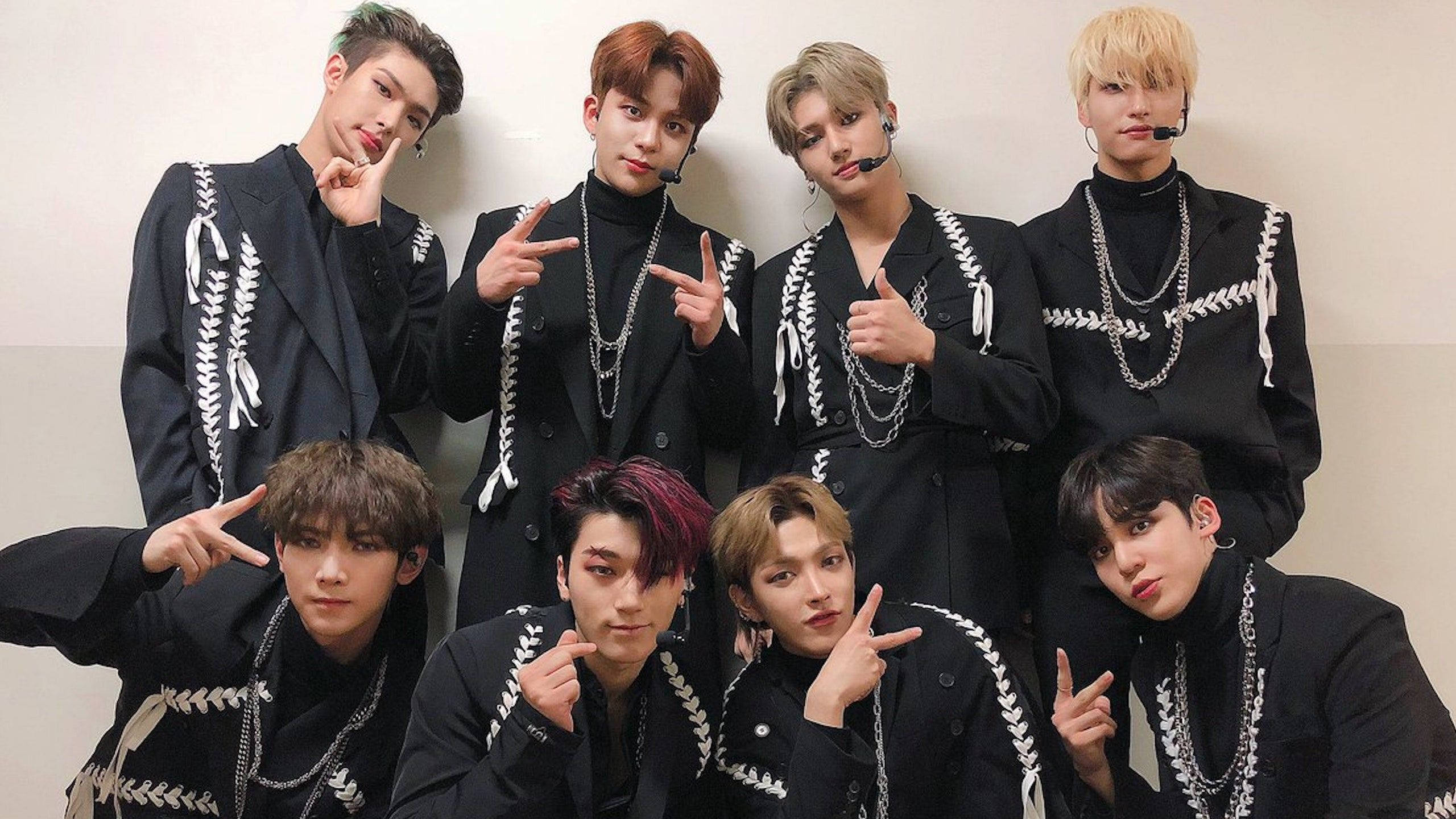 Ateez穿黑色西裝桌面 壁紙 — 七位時尚年輕男士身穿搭配黑色服裝，飾有白色蕾絲細節，自信地靠著素牆擺姿勢。