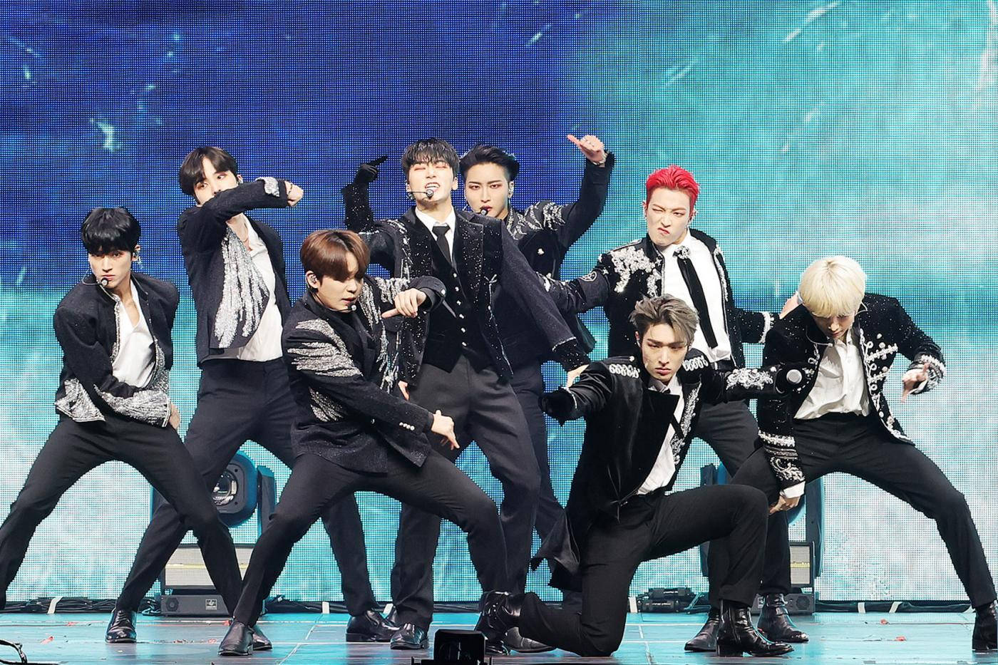ATEEZ跳舞姿勢 壁紙 — 一個K-pop組合在藍色數碼背景前穿著黑色閃片外套，在舞台上充滿活力地表演。
