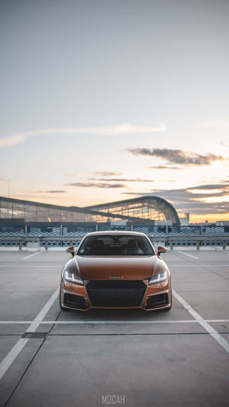銅色 Audi TT 停喺日落時分嘅空停車場。