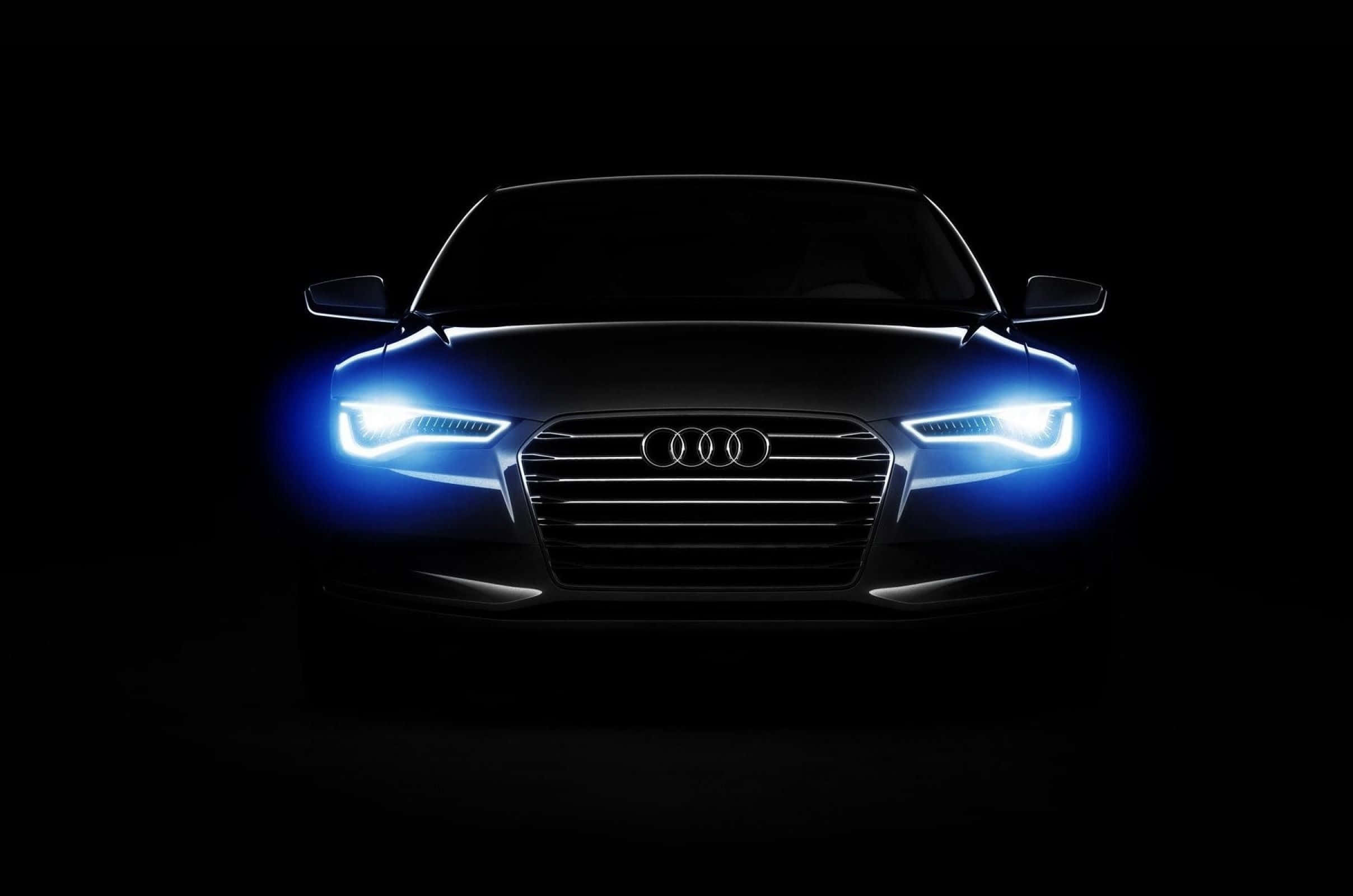 Audi A6 桌布 壁紙 — Audi 汽車正面視圖，帶有發光藍色車頭燈，背景漆黑一片。