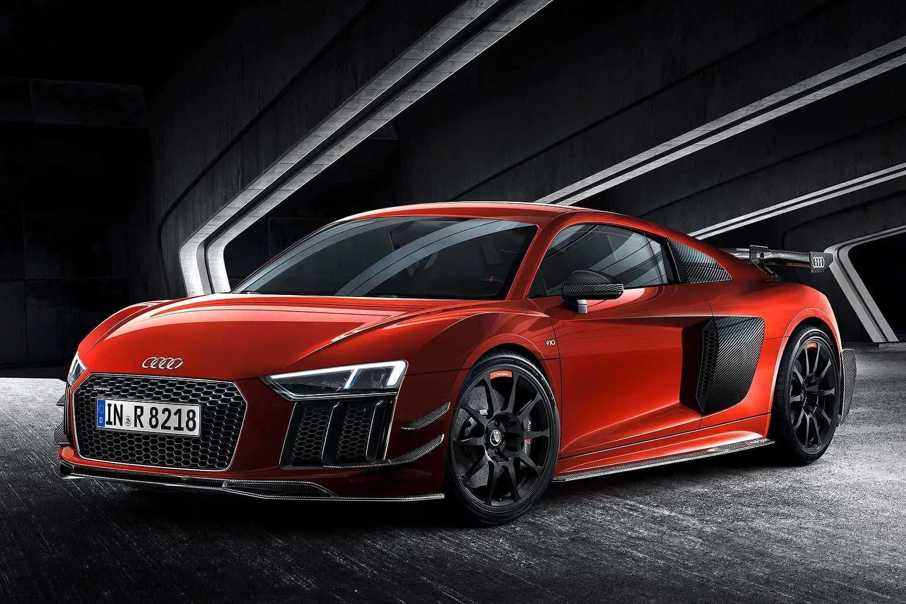 體驗 Audi R8 的澎湃動力 壁紙 — 一輛時尚的紅色奧迪R8跑車在現代混凝土隧道中，在戲劇性燈光下閃閃發光。