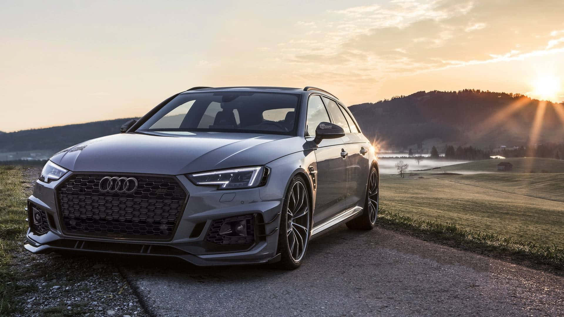 Audi Rs4 桌布 壁紙 — 一輛時尚的銀色奧迪RS4 Avant停在日落時分的碎石路上，金色的光線在起伏的山丘上投下長長的影子。