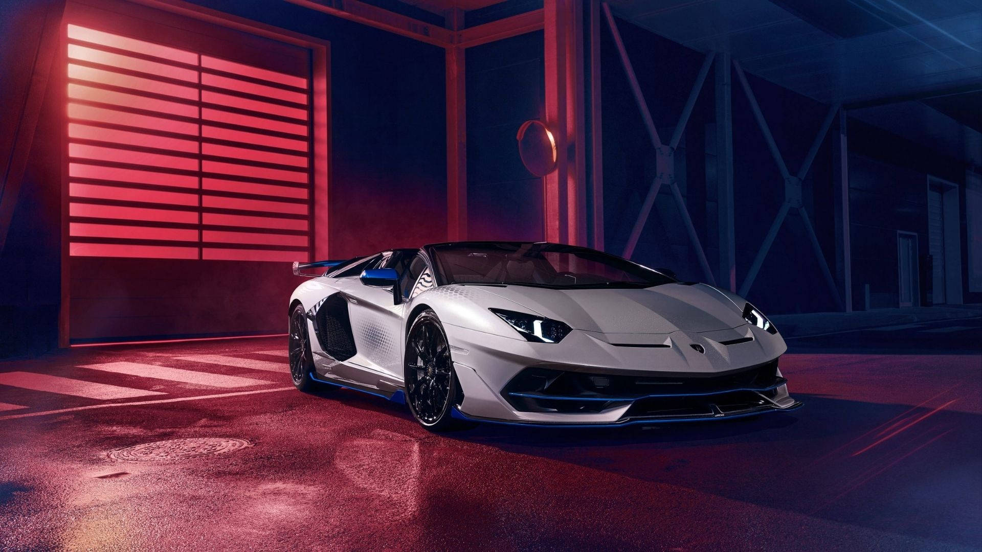 標題：令人驚艷的蘭博基尼Aventador SVJ Xago午夜藍 壁紙 — 一架時尚的銀色林寶堅尼 Aventador SVJ 停泊在昏暗的車庫中，沐浴在戲劇性的紅藍燈光下。