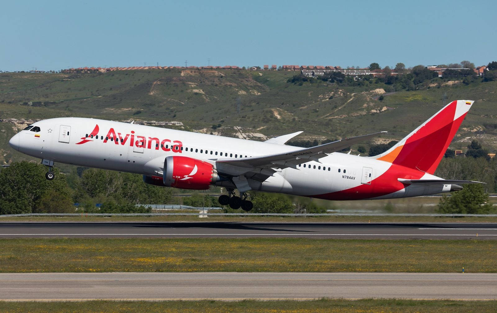 Avianca 飛機從有綠色山丘和藍天的跑道起飛。