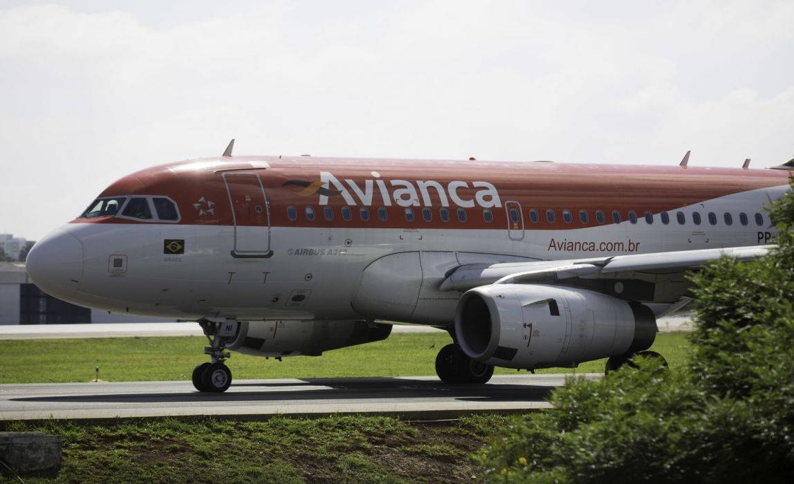 Avianca 飛機在跑道上，附近有綠草和灌木。