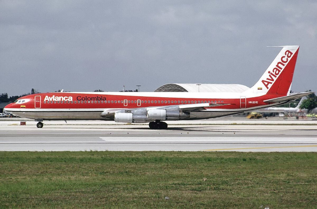 多雲天空下，機場停機坪上的紅白相間 Avianca Colombia 飛機。