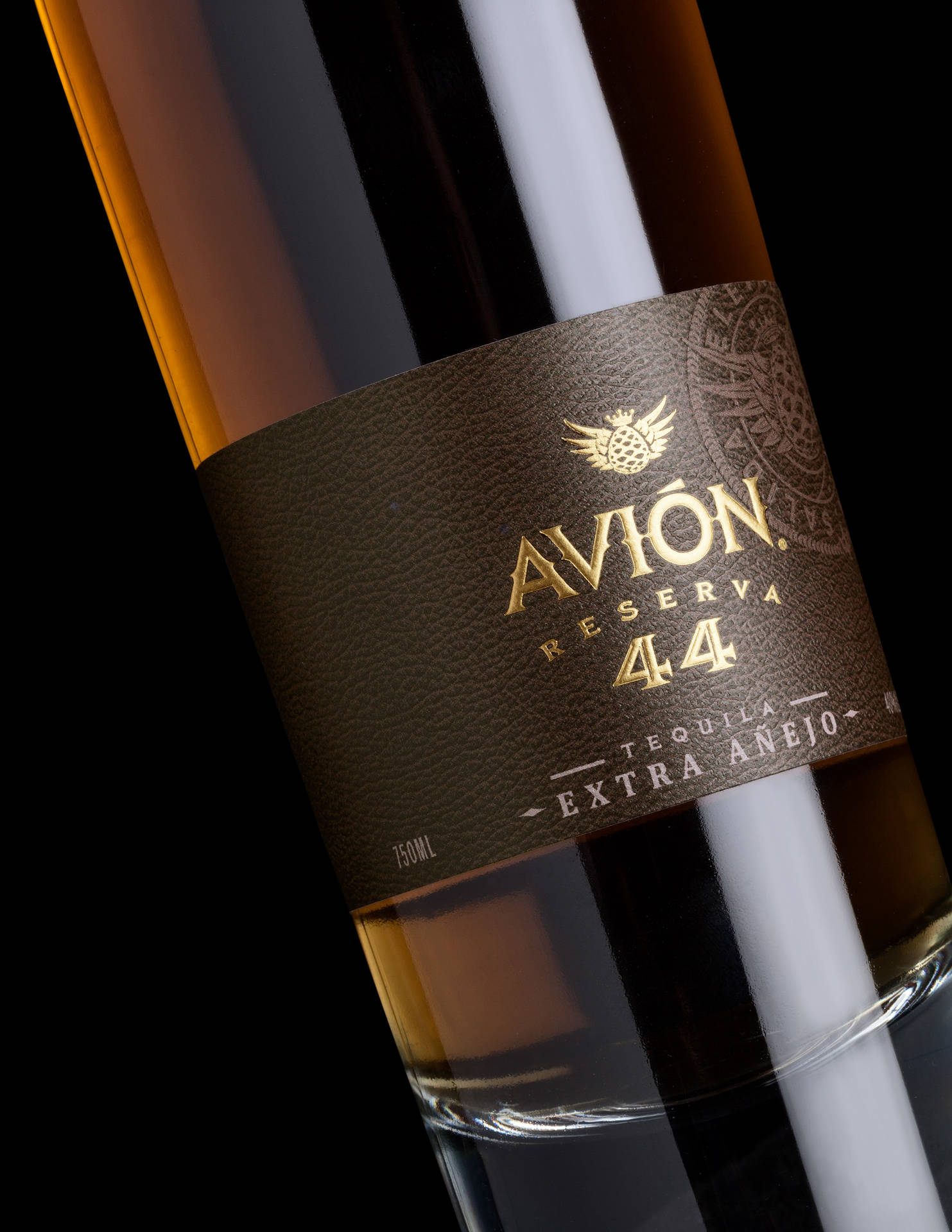 Avion Reserva 44 龍舌蘭酒瓶標籤特寫，深棕色紋理背景上印有金色文字。