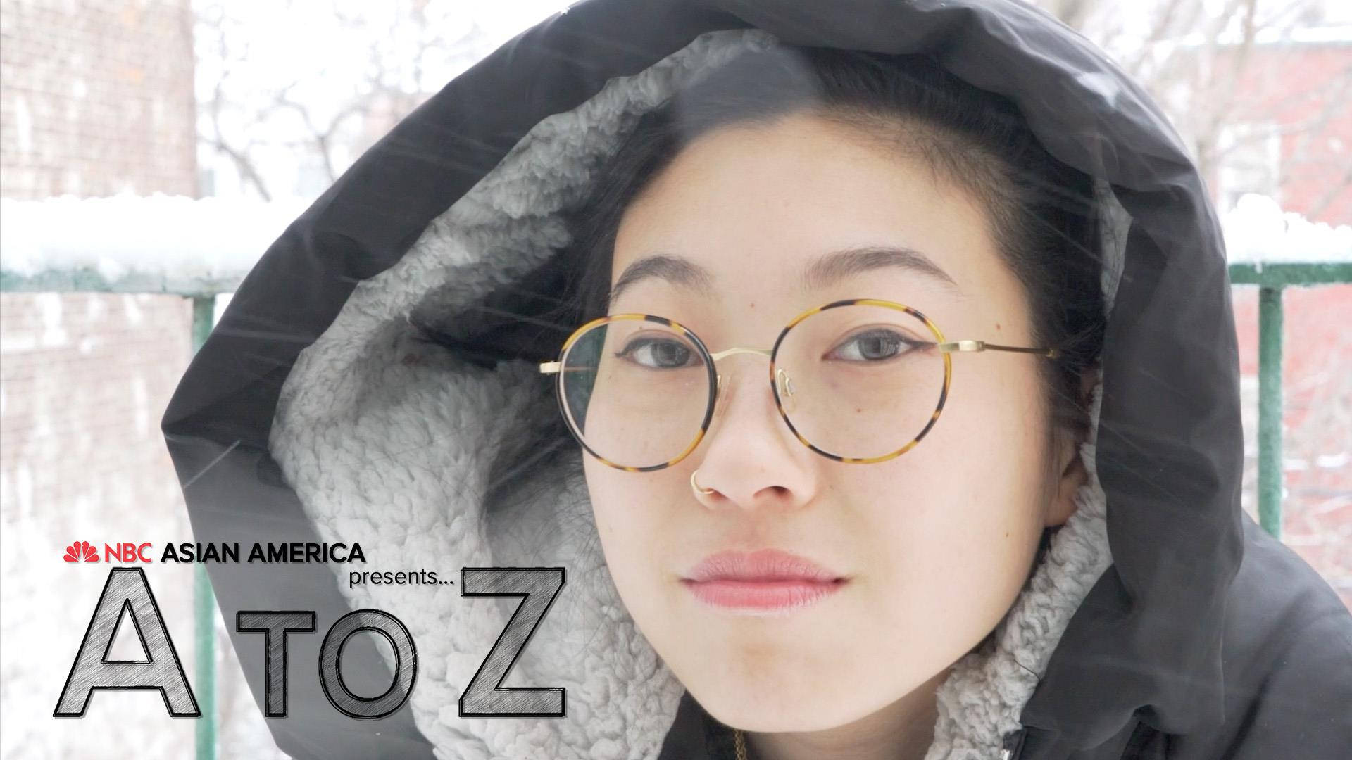 Awkwafina 冬季夾克 壁紙 — 一位戴著圓框眼鏡和黑色連帽外套的年輕女子在雪天平靜地凝視著相機。