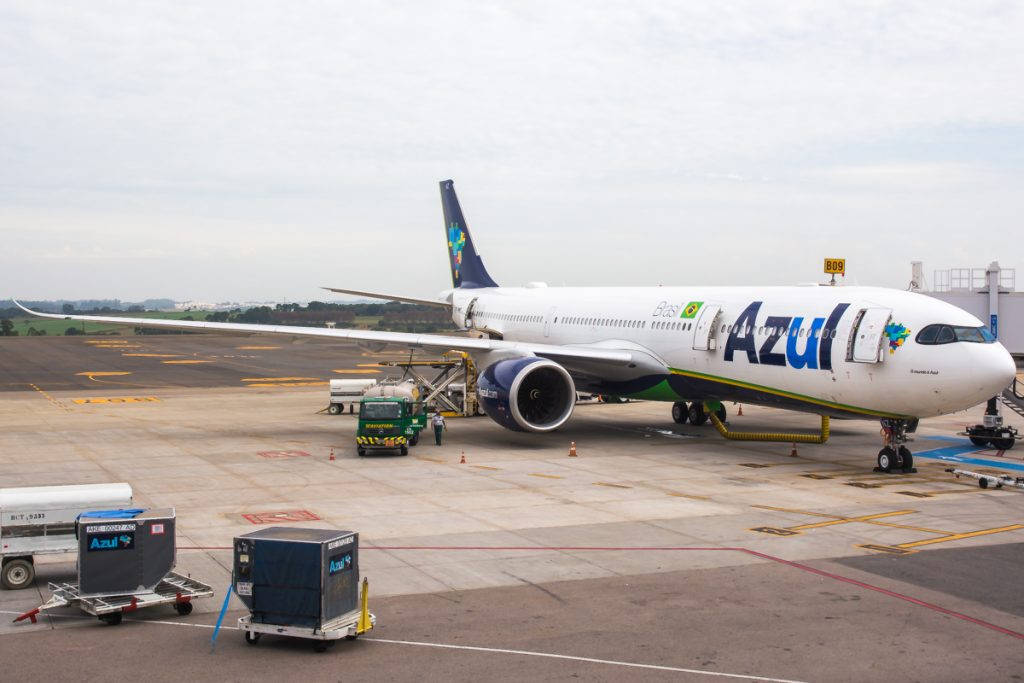 Azul Airlines飛機停在機場閘口，有地勤人員和設備。