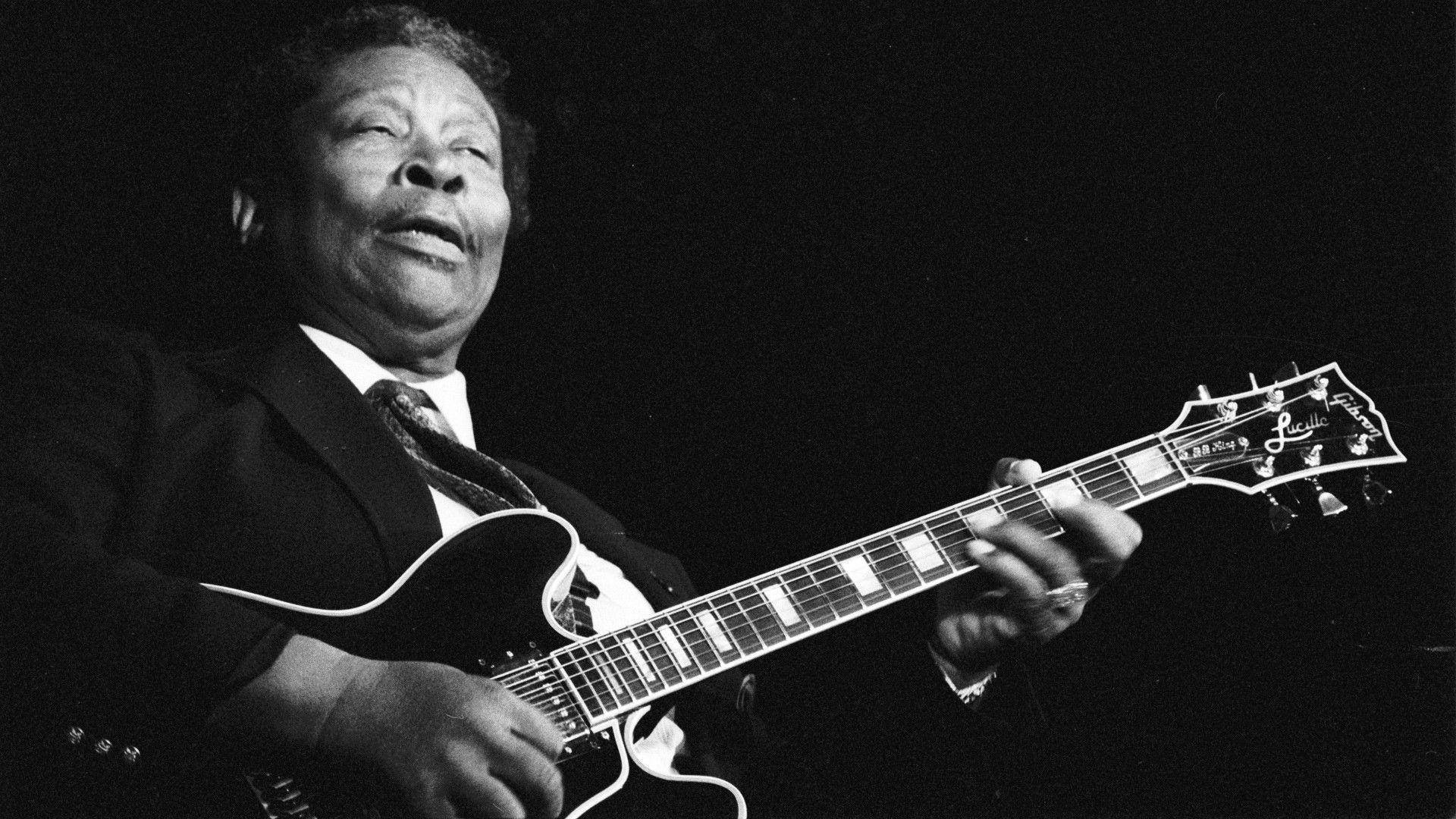 B.B. King黑白攝影壁紙 壁紙 — 一位傳奇藍調結他手在黑白照片中，於戲劇性的舞台燈光下熱情地彈奏電結他。