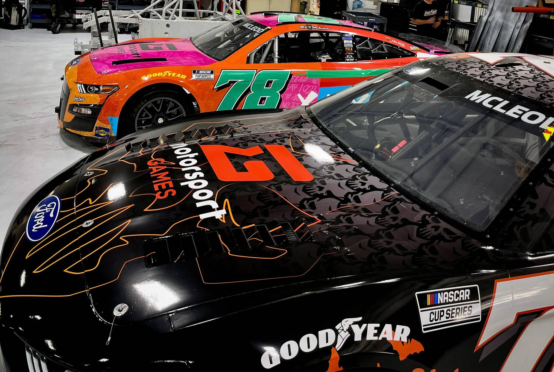 兩輛帶有鮮豔貼花的NASCAR賽車停放在車庫中。