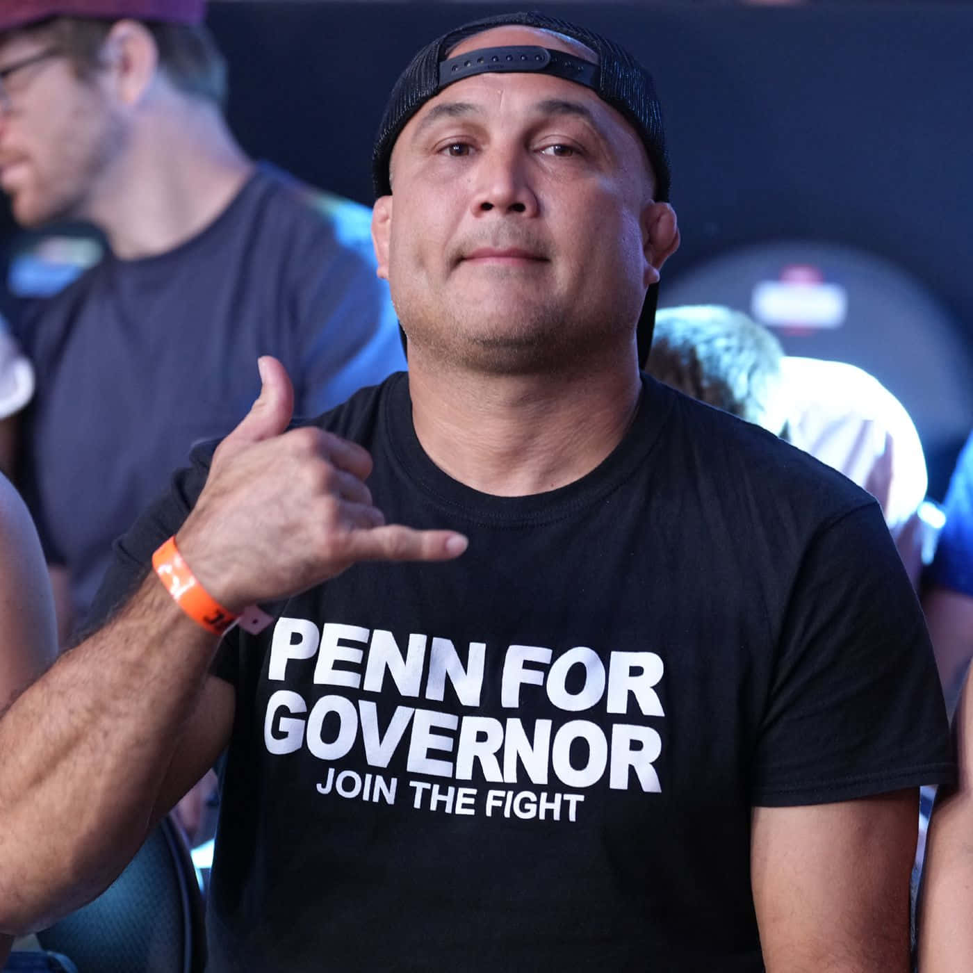 身穿「Penn for Governor」襯衫的男子在活動中做出沙卡手勢。