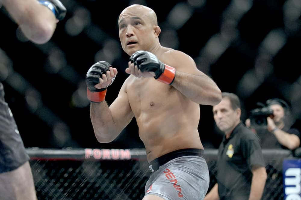一位穿著灰色短褲的男性MMA戰士在比賽中於八角籠內揮拳。