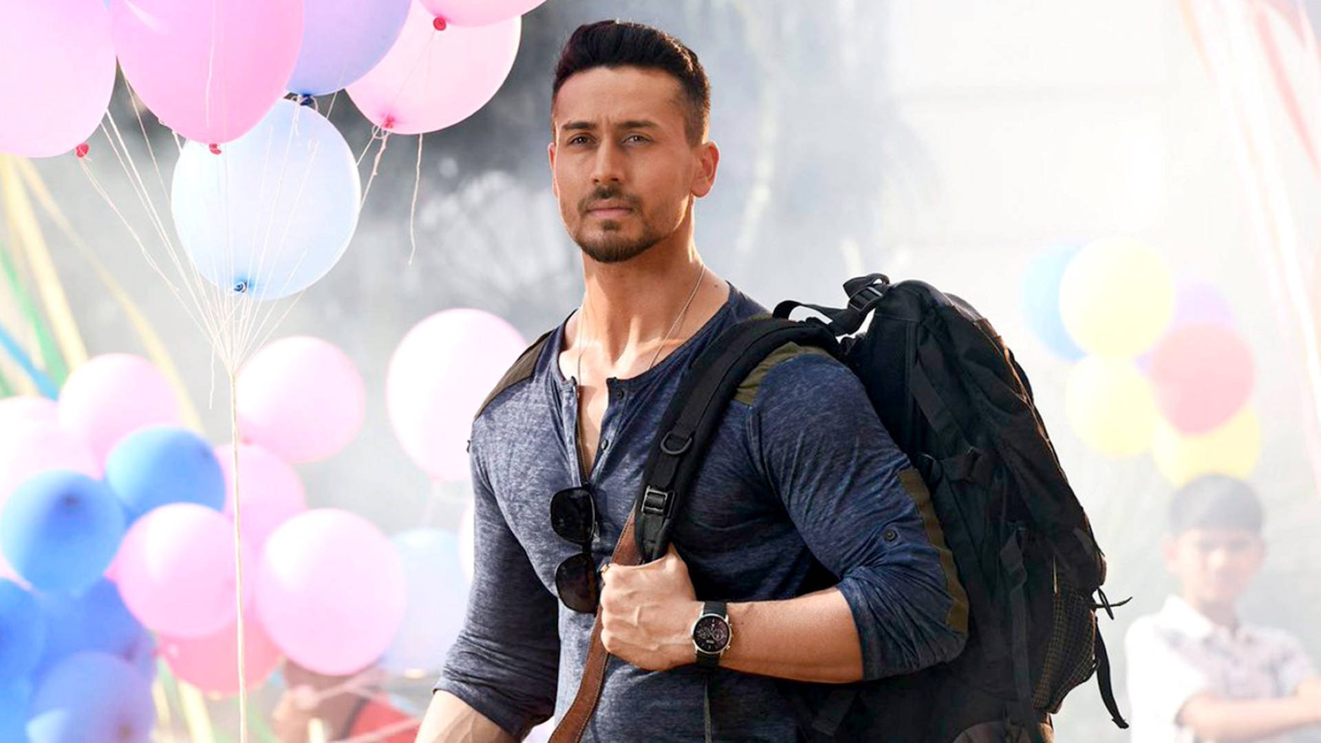 提格·沙夫在《Baaghi 2》中 壁紙 — 一個背著背包的男人自信地站在色彩繽紛的氣球中，於一個節日戶外活動。