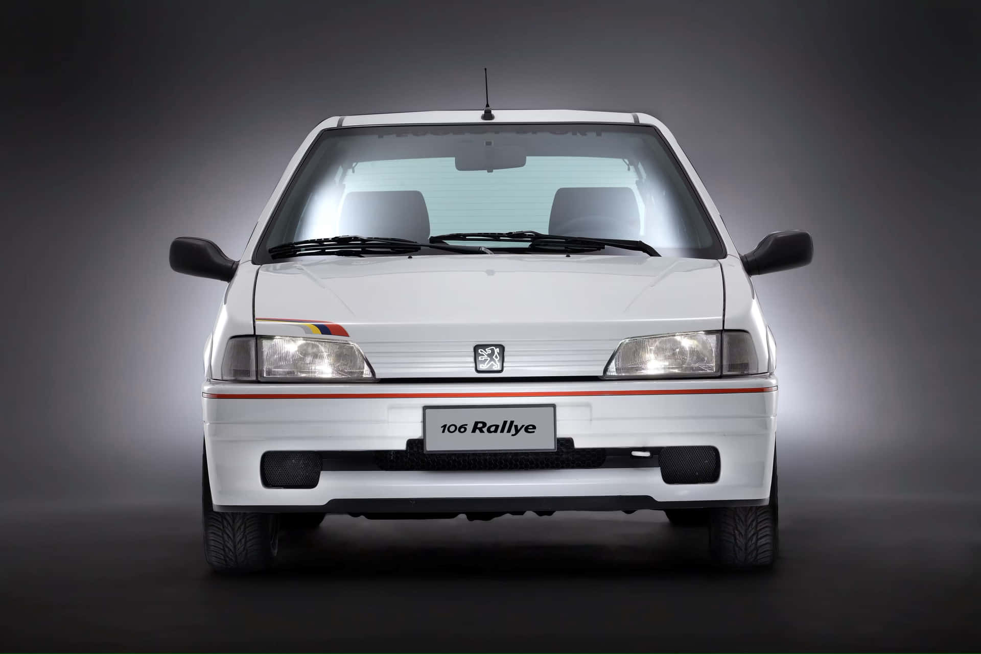  壁紙 — 白色標緻106 Rallye汽車的前視圖，帶有紅色條紋和點亮的前燈，背景為深色工作室。