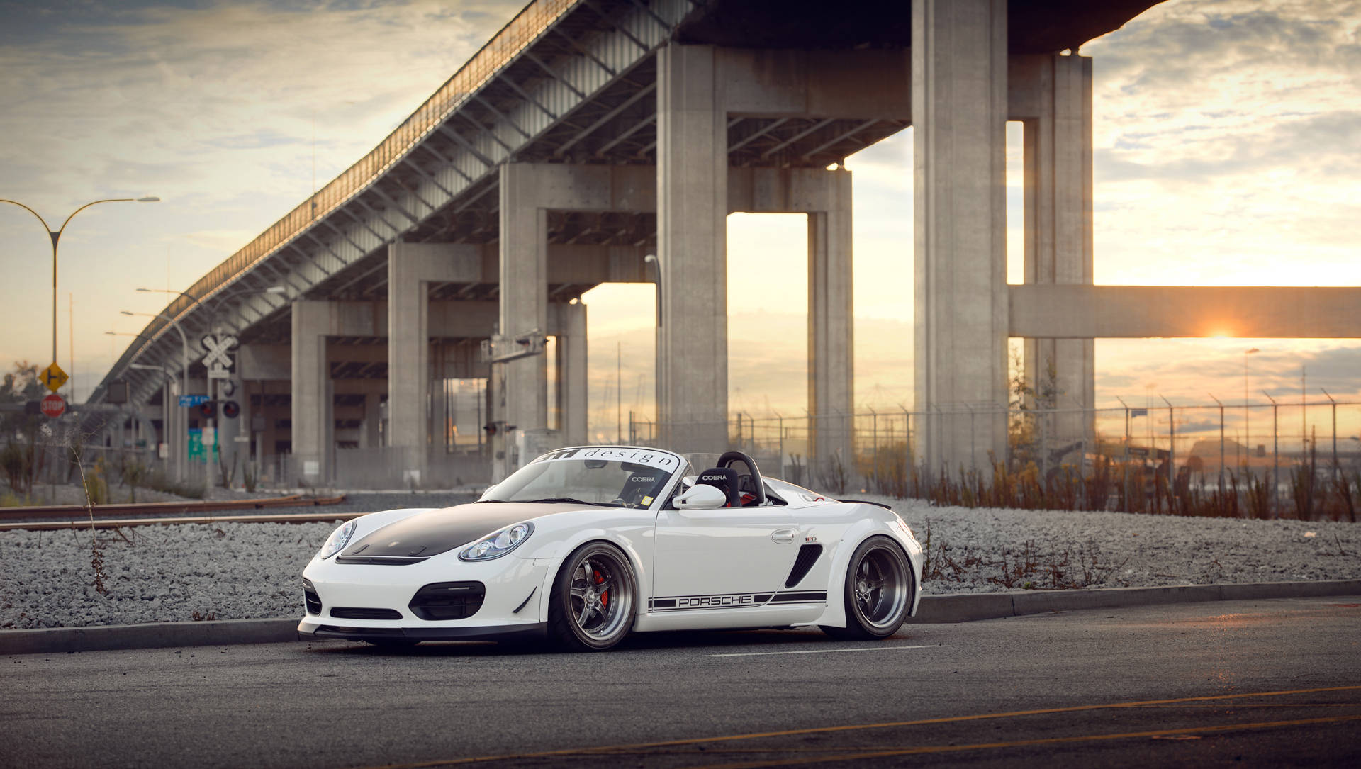 動感奢華 - 2016款白色保時捷Boxster Spyder 壁紙 — 一輛白色保時捷Boxster開篷車停泊在混凝土天橋下，正值黃金時段，溫暖的陽光穿透而過。