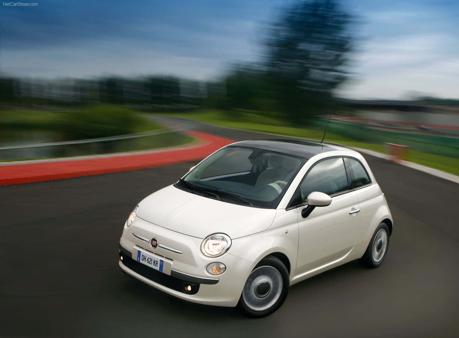 Fiat 500l 桌布 壁紙 — 一輛白色Fiat 500在蜿蜒的賽道上巡航，背景是模糊的綠化和紅色路緣。