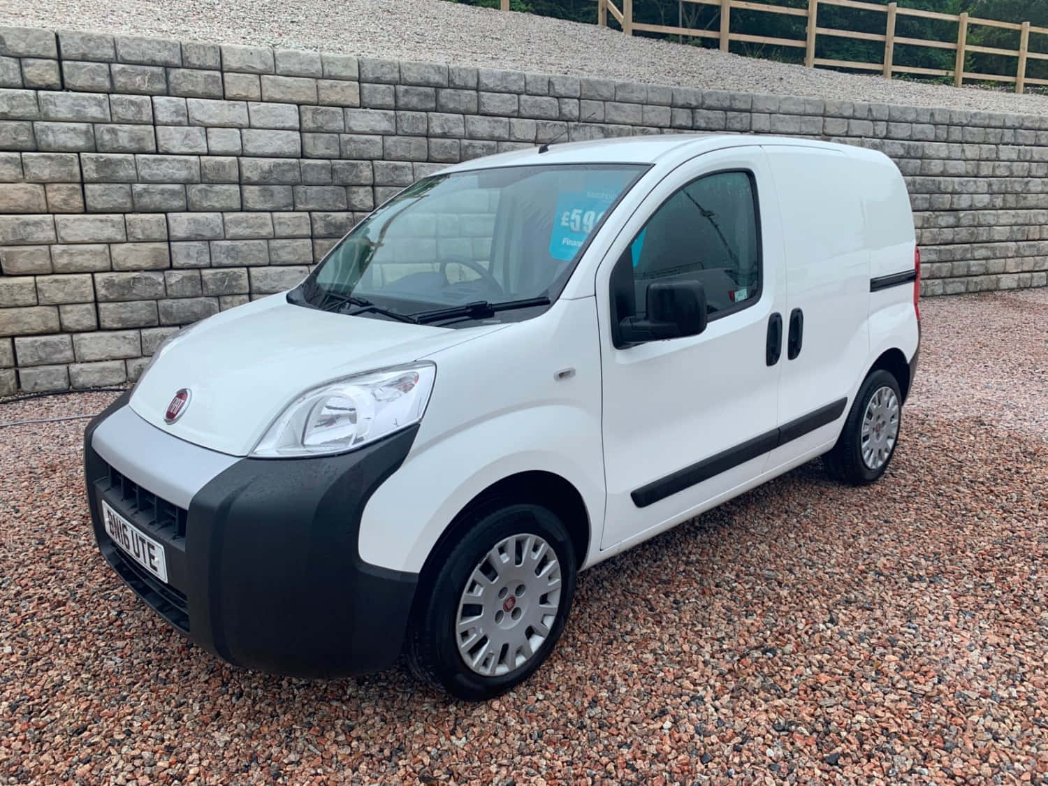 Fiat Fiorino 桌布 壁紙 — 一輛白色 Fiat Fiorino 客貨車停泊在碎石上，背景有石牆和木柵欄。