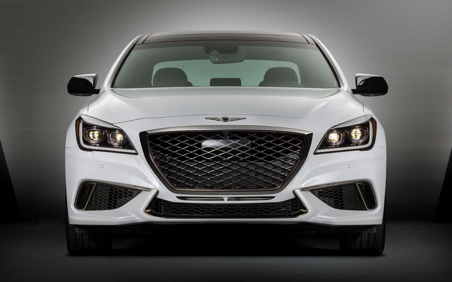 Genesis G80 桌布 壁紙 — 一輛純白色豪華轎車正面朝前，配備發光頭燈和醒目進氣格柵，背景為深色工作室。