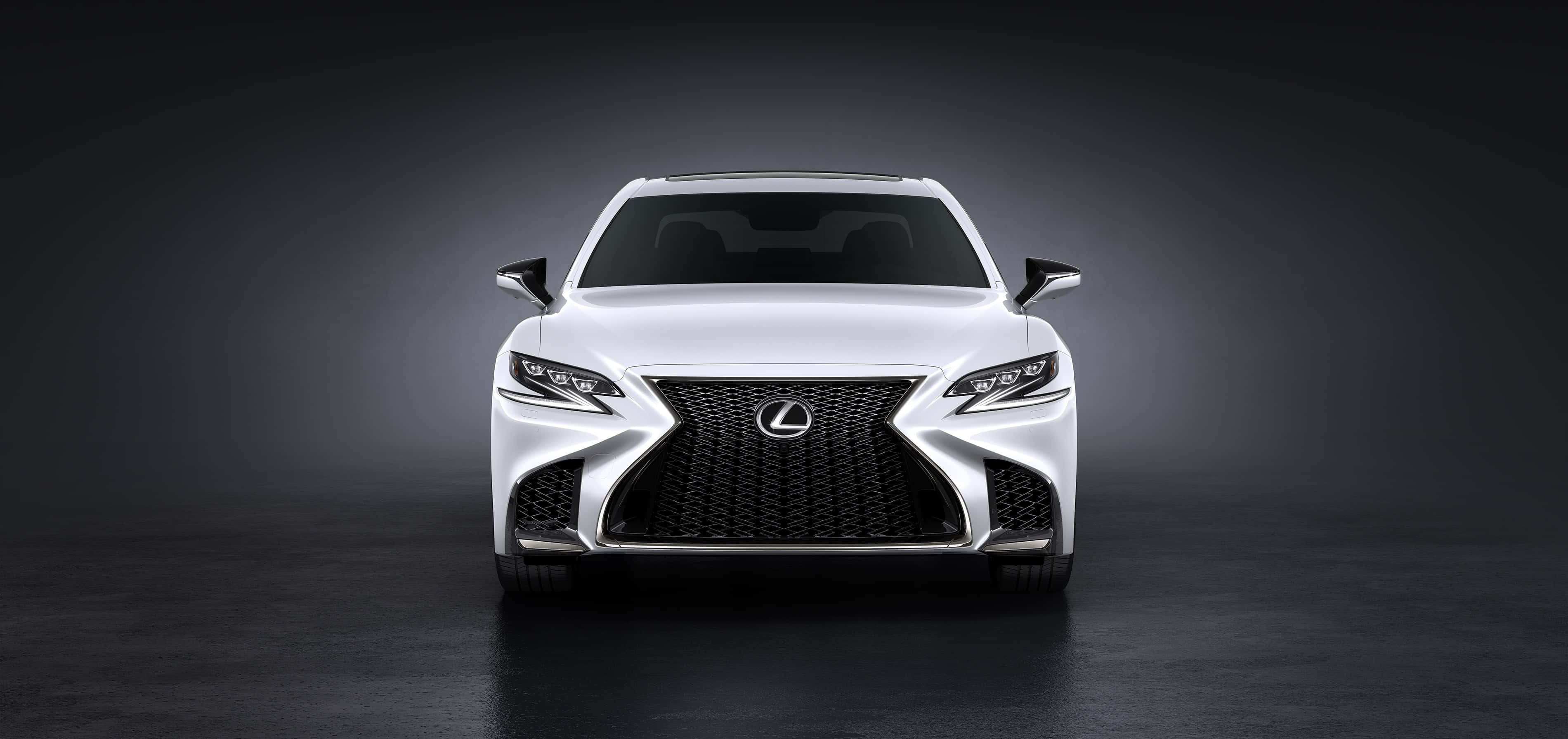 Lexus Ls 500 桌布 壁紙 — 一輛純白色的凌志房車在昏暗的攝影棚中正面朝前，戲劇性的燈光凸顯其銳利的水箱護罩和時尚的頭燈。