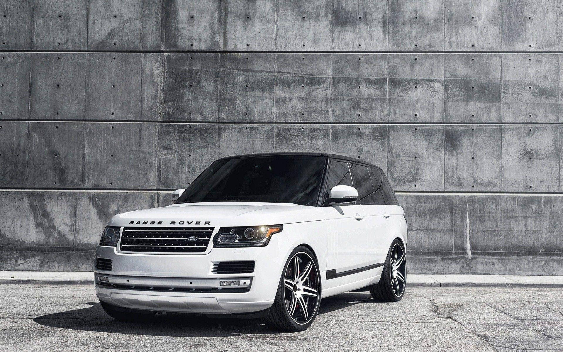 白色Range Rover SUV配備定制輪圈，停靠在混凝土牆前。