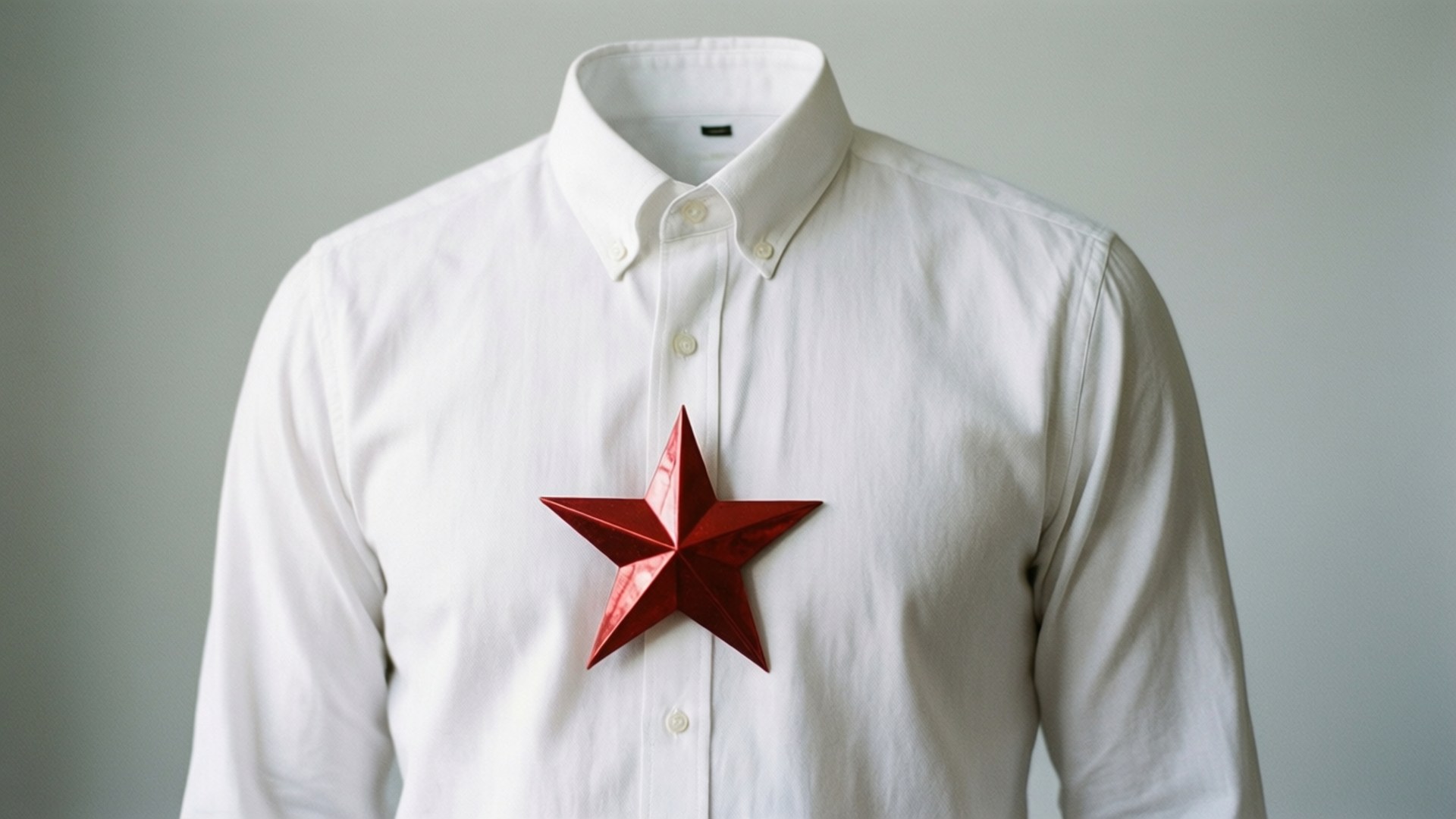 Christmas Shirt 桌布 壁紙 — 一件挺括的白色鈕扣襯衫，在純灰色背景上，胸前別著一枚醒目的紅色金屬星星。