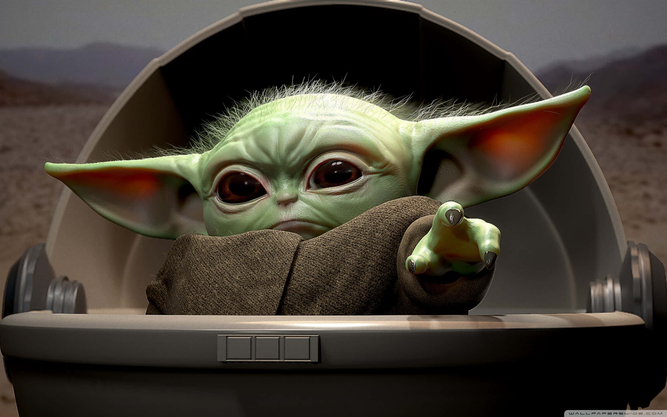 Baby Yoda 風格指著手指 壁紙 — 一個綠色皮膚、大耳朵、眼神充滿表情的嬰兒尤達坐在太空船艙中，手指向前方。