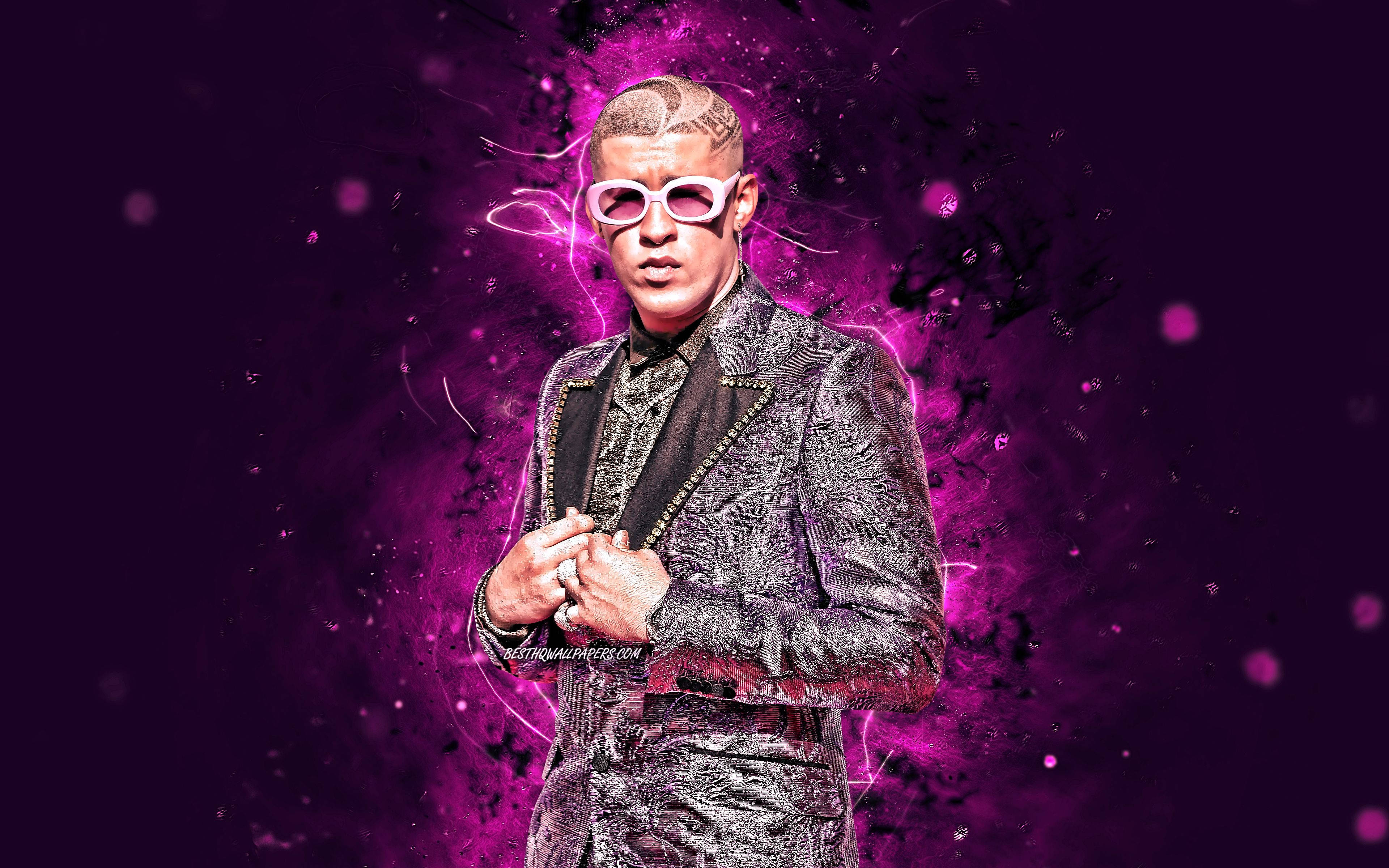 Bad Bunny 穿奢華深紫色大衣 壁紙 — 一個穿著質感西裝和白色太陽眼鏡的男人站在充滿活力的紫色電能爆發背景前。