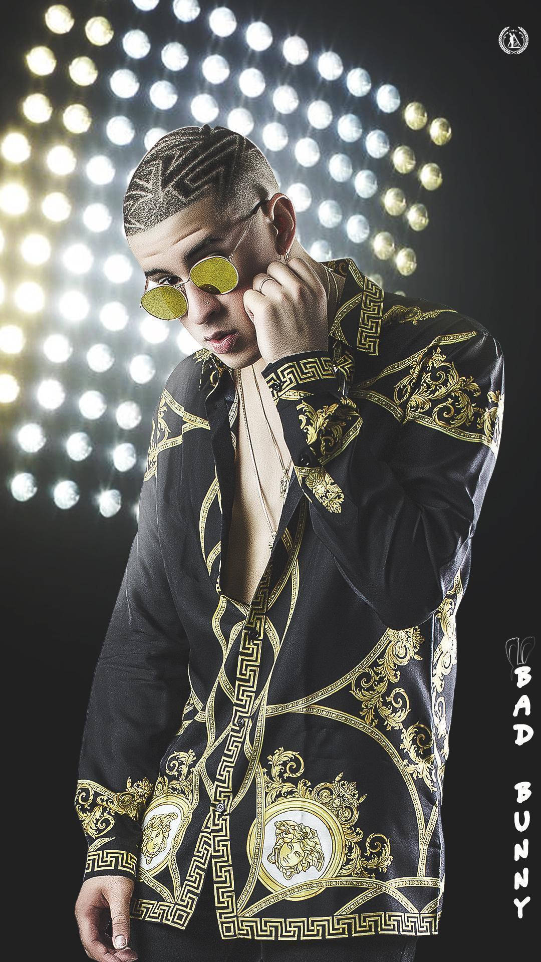 Bad Bunny 黑色 Versace 長袖Polo衫 壁紙 — 一位時尚男士身穿黑金華麗外套，在明亮的圓形燈光網格下擺姿勢，戴著黃色圓形太陽眼鏡。