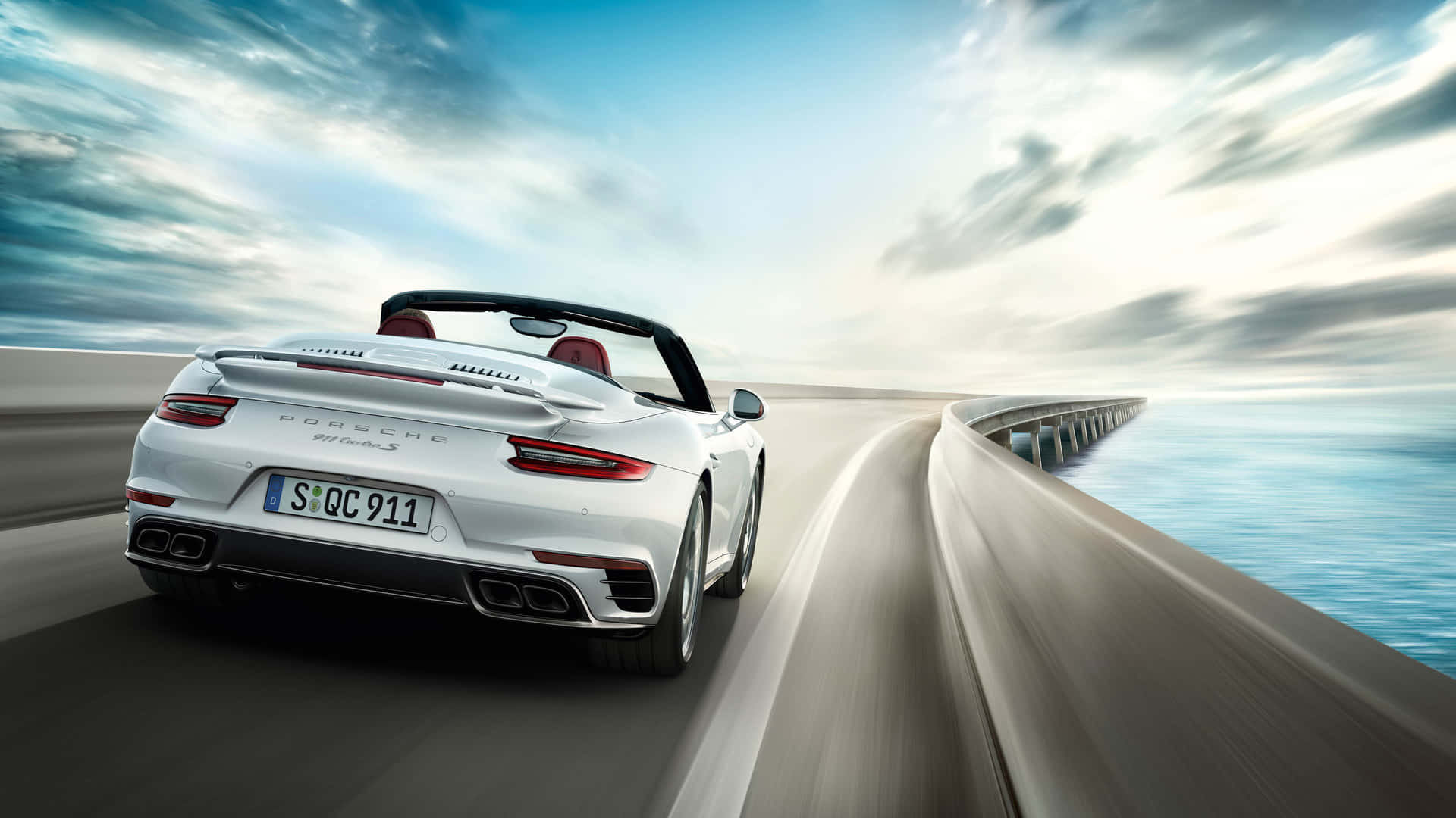 白色保時捷911 Turbo S開篷跑車在日落時分於海岸高速公路上奔馳。