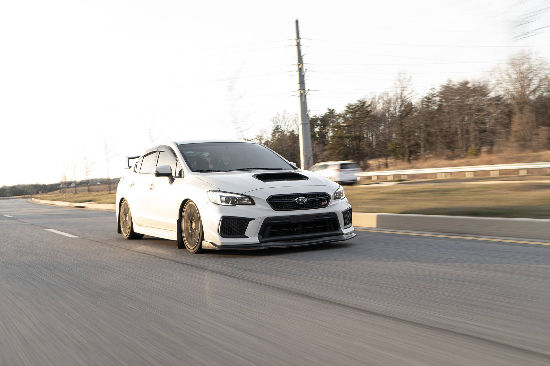 白色Subaru WRX STI在高速公路上行駛，背景模糊。