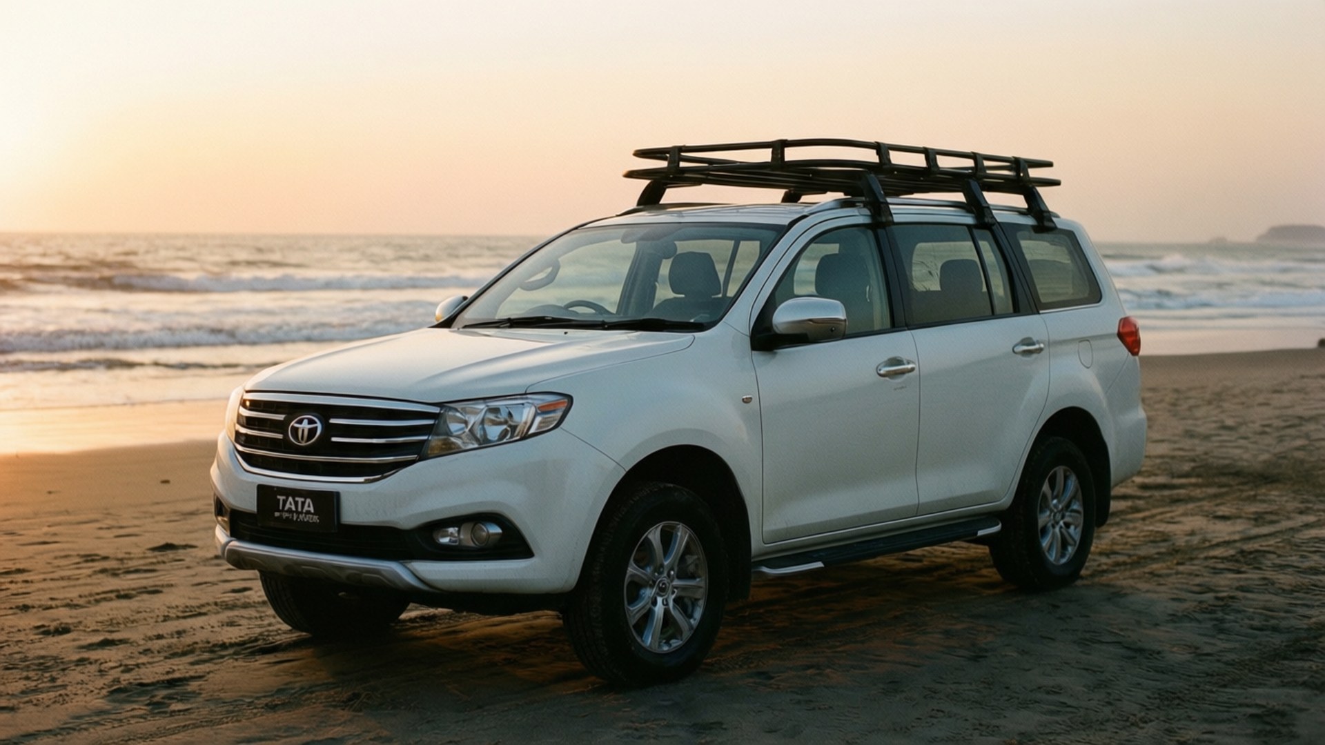 Tata Motors 桌布 壁紙 — 一輛白色Tata Safari SUV配備車頂行李架，停泊在日落時分的沙灘上，背景有海浪。