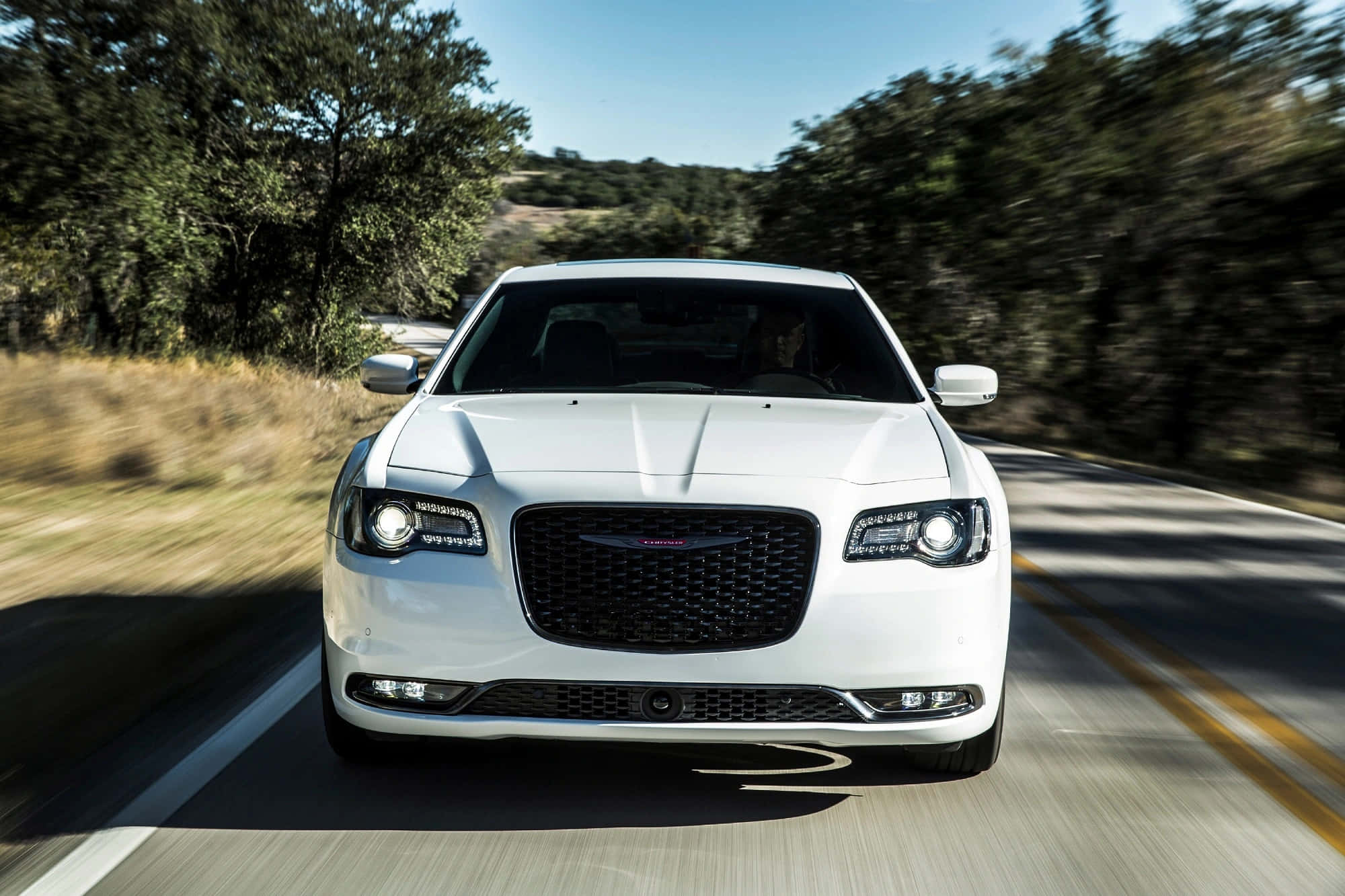Chrysler 300 桌布 壁紙 — 一輛白色豪華轎車在陽光明媚的鄉村道路上疾馳，兩旁是茂密的綠樹。