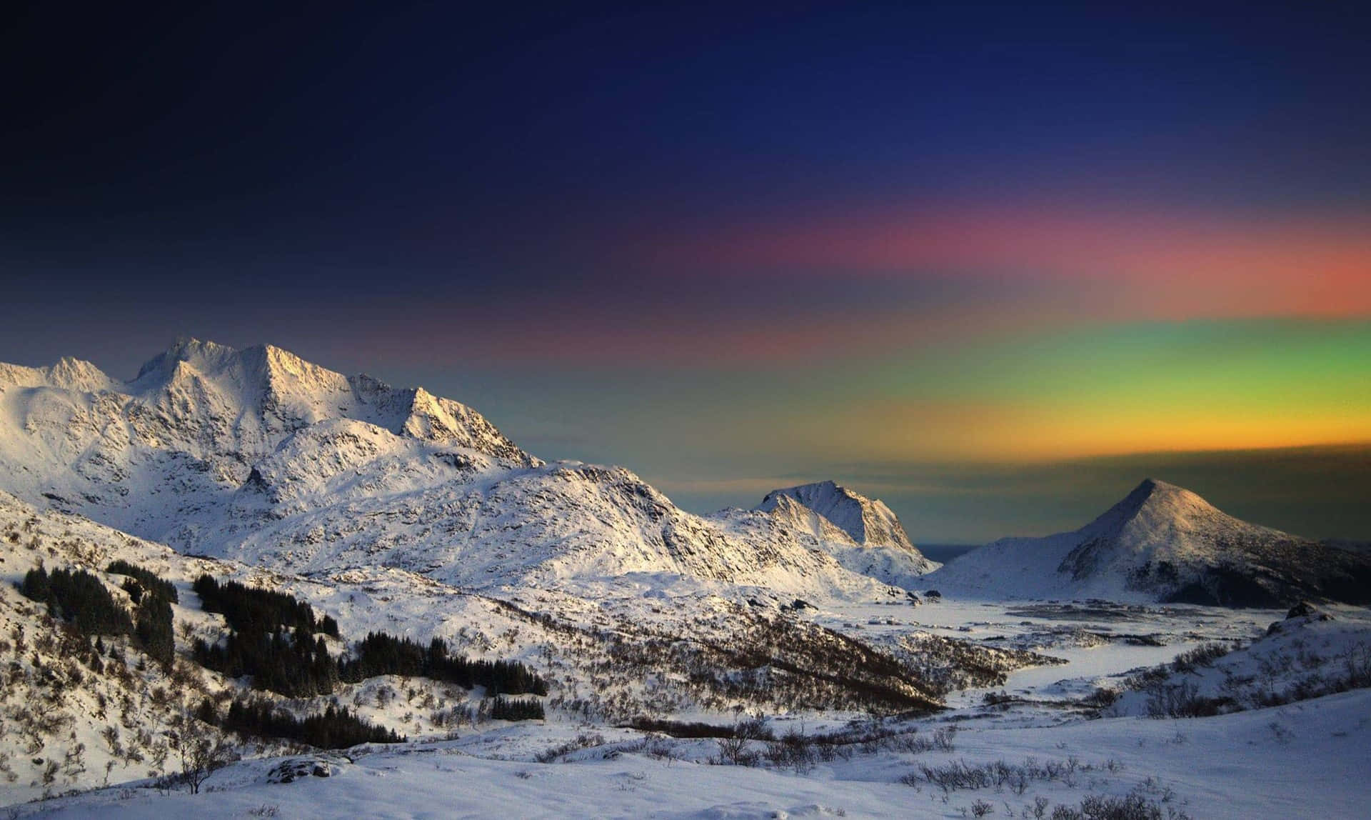 Colorful Sunset 桌布 壁紙 — 白雪覆蓋的山峰在絢麗的極光下閃耀，極光以綠色、黃色和粉紅色調渲染了暮色天空。