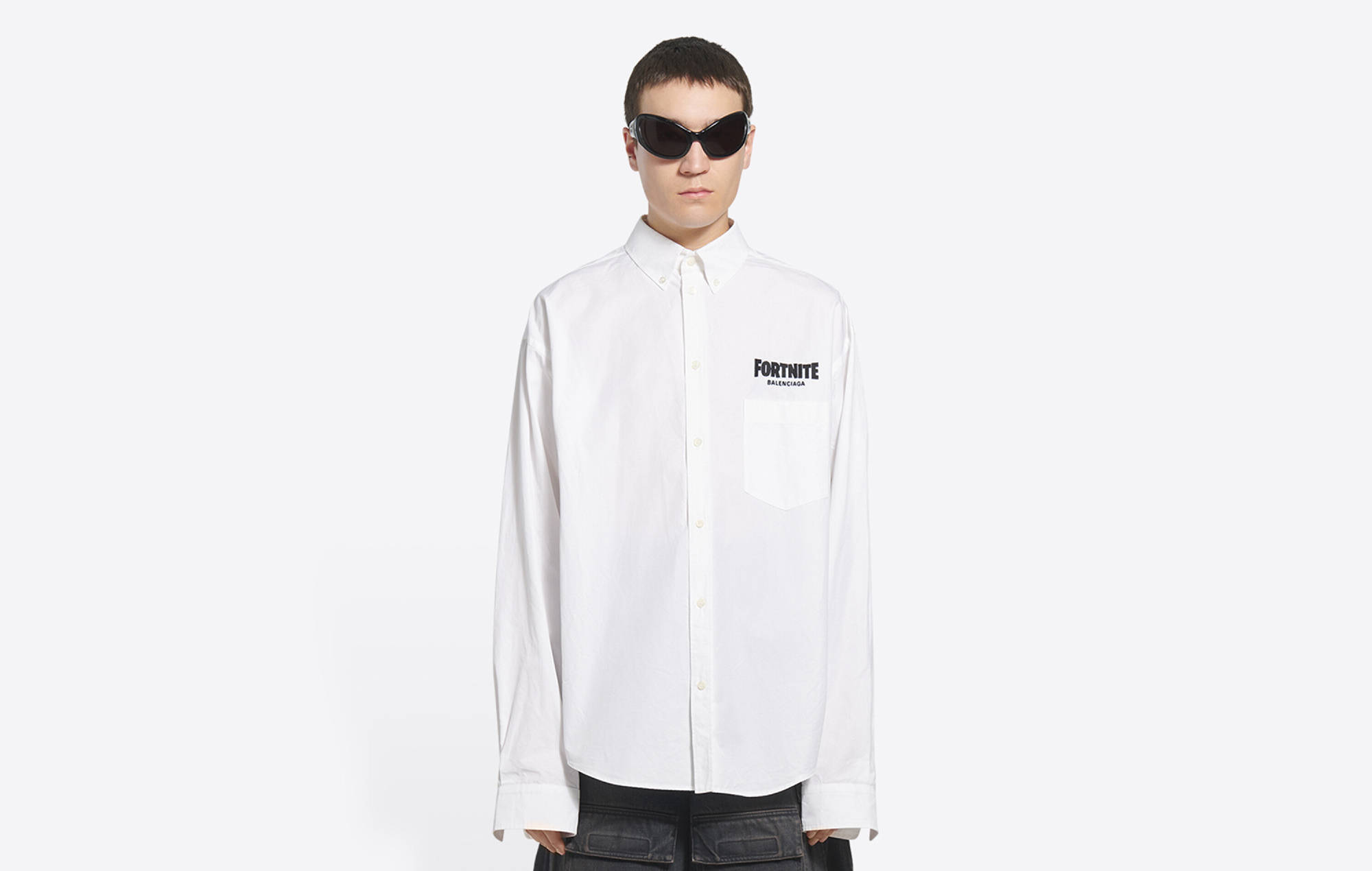Balenciaga 白色長袖襯衫 壁紙 — 一個人穿著白色鈕扣襯衫，胸前有Fortnite標誌，戴著深色太陽眼鏡，站在純白色背景前。