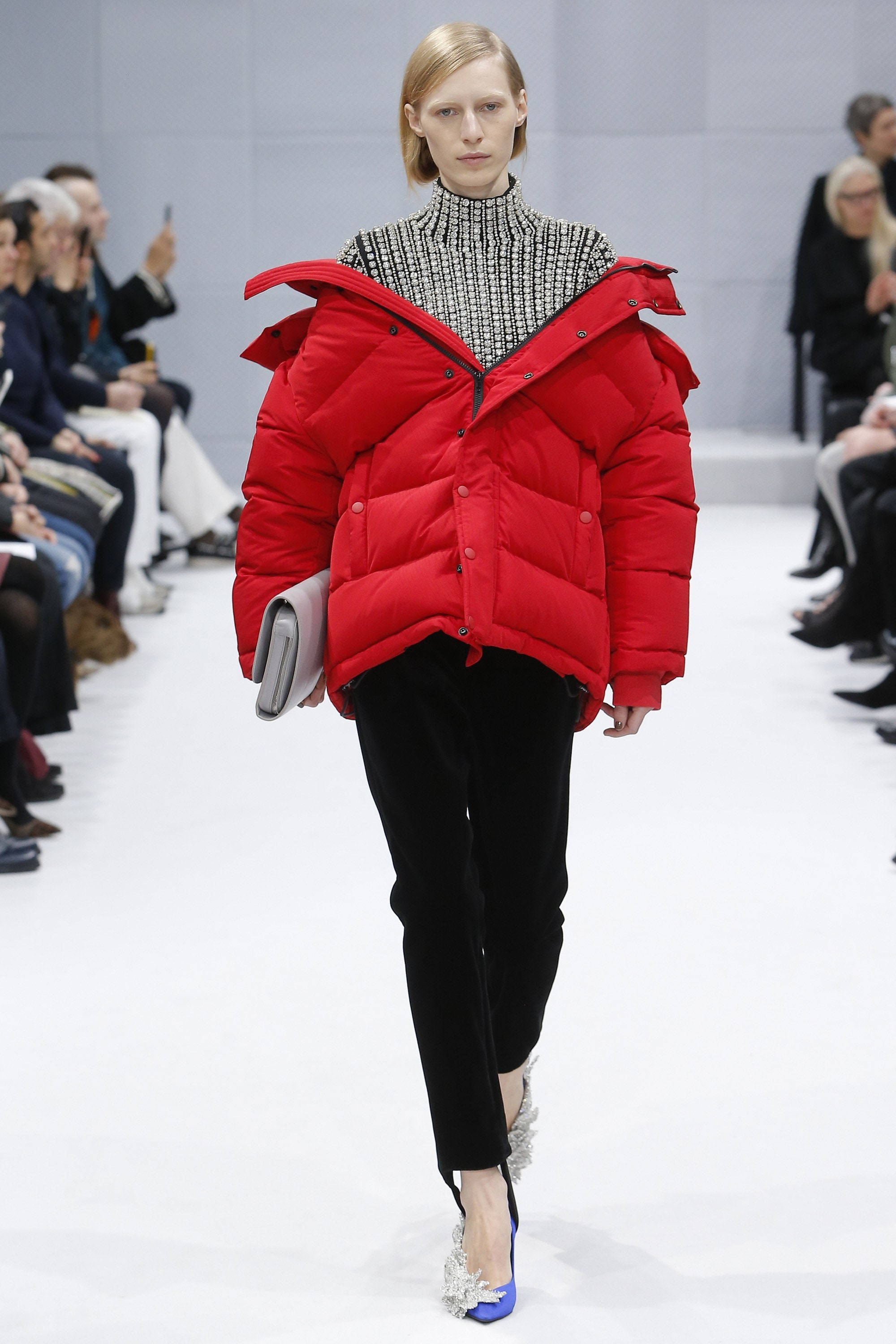 模特身穿 Balenciaga 紅色外套 壁紙 — 模特兒穿著一件大膽的紅色羽絨外套（ oversized 肩部）和黑色褲子走在天橋上。