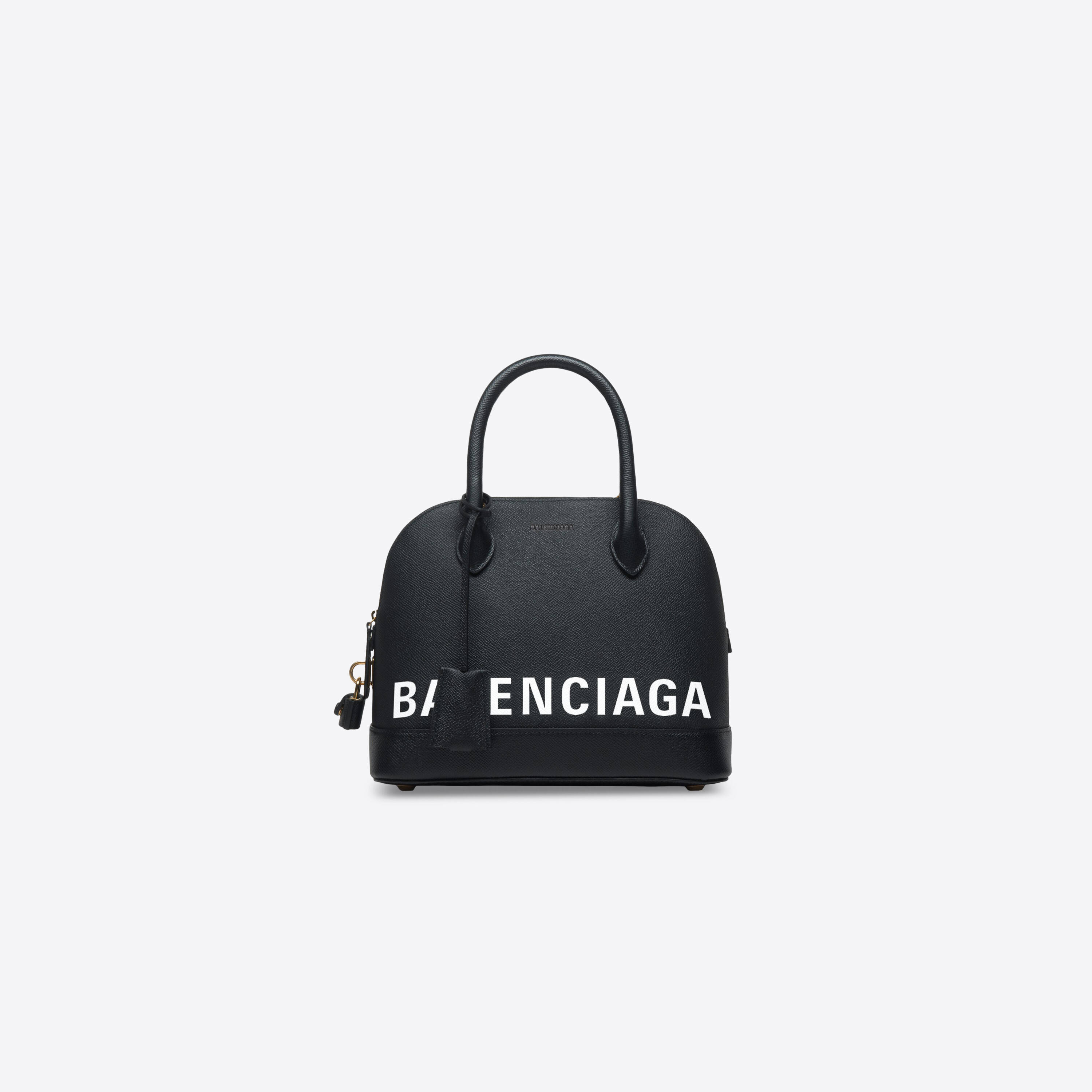 Balenciaga 紐約手袋 壁紙 — 一個時尚的黑色Balenciaga手袋，帶有粗體白色標誌文字和金色五金件，背景為純白色。