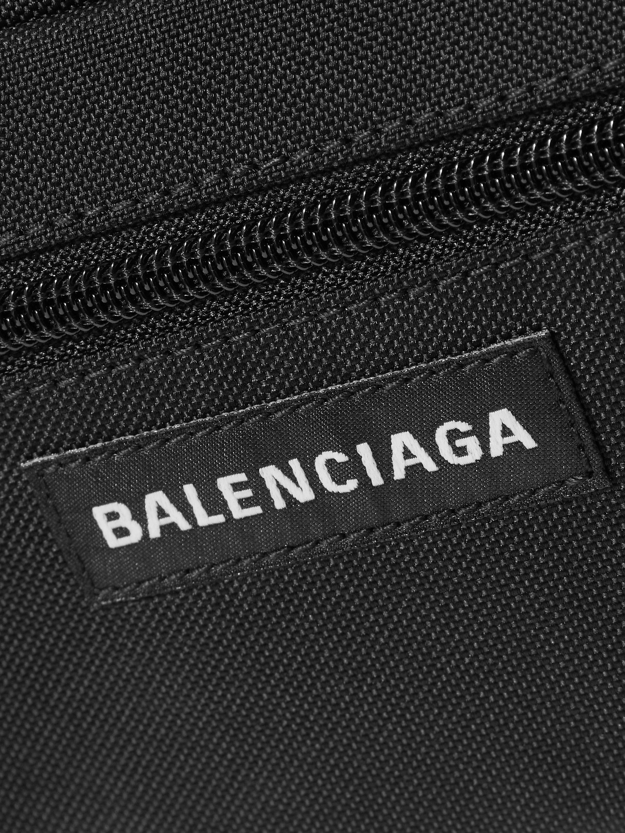 Balenciaga 包袋標誌 壁紙 — 黑色Balenciaga手袋特寫，展示紋理布料拉鍊和白色刺繡品牌標籤。