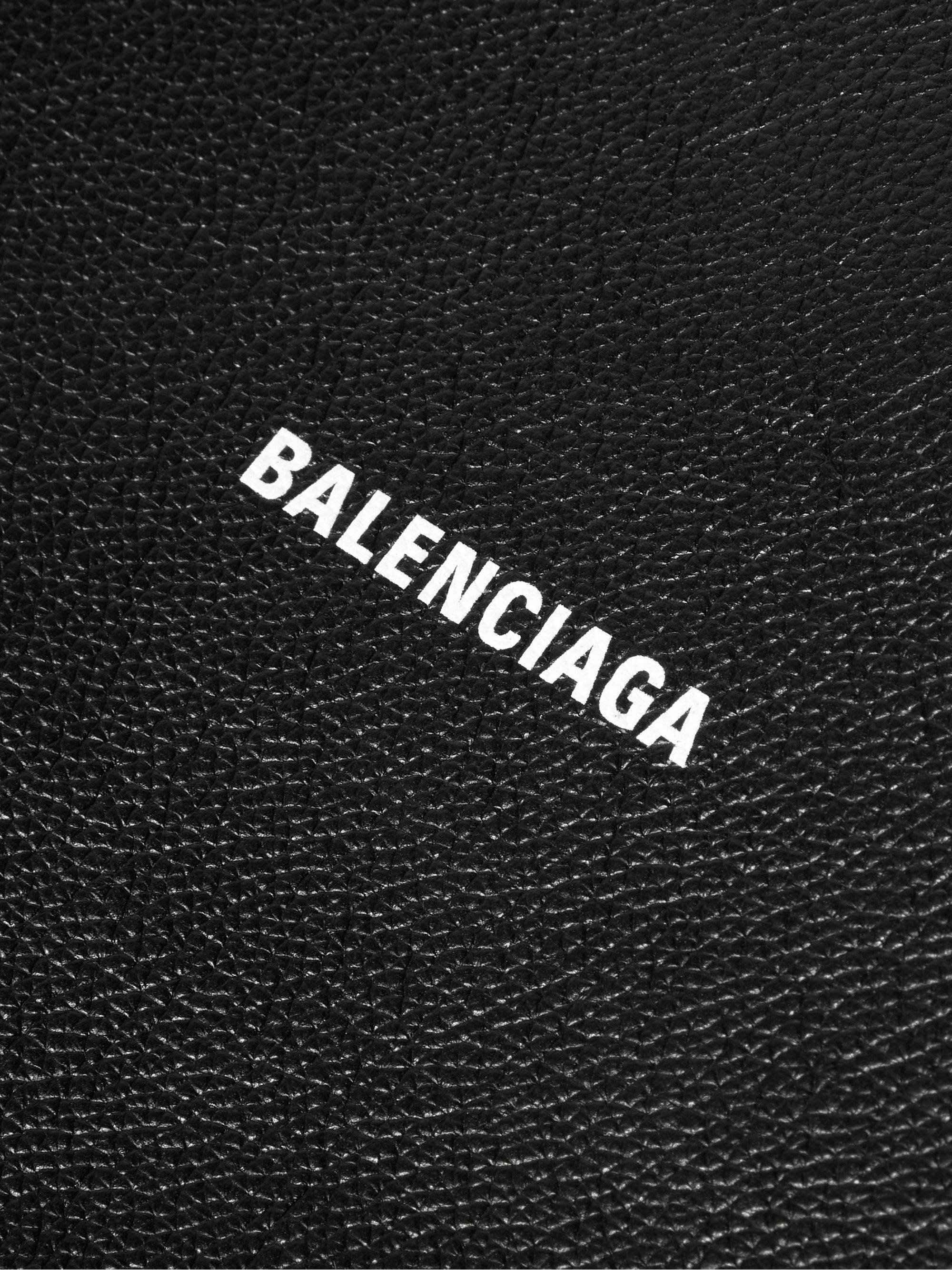 Balenciaga 標誌印於皮革 壁紙 — 黑色紋理皮革表面的特寫，上面有粗體白色字母 'BALENCIAGA'。